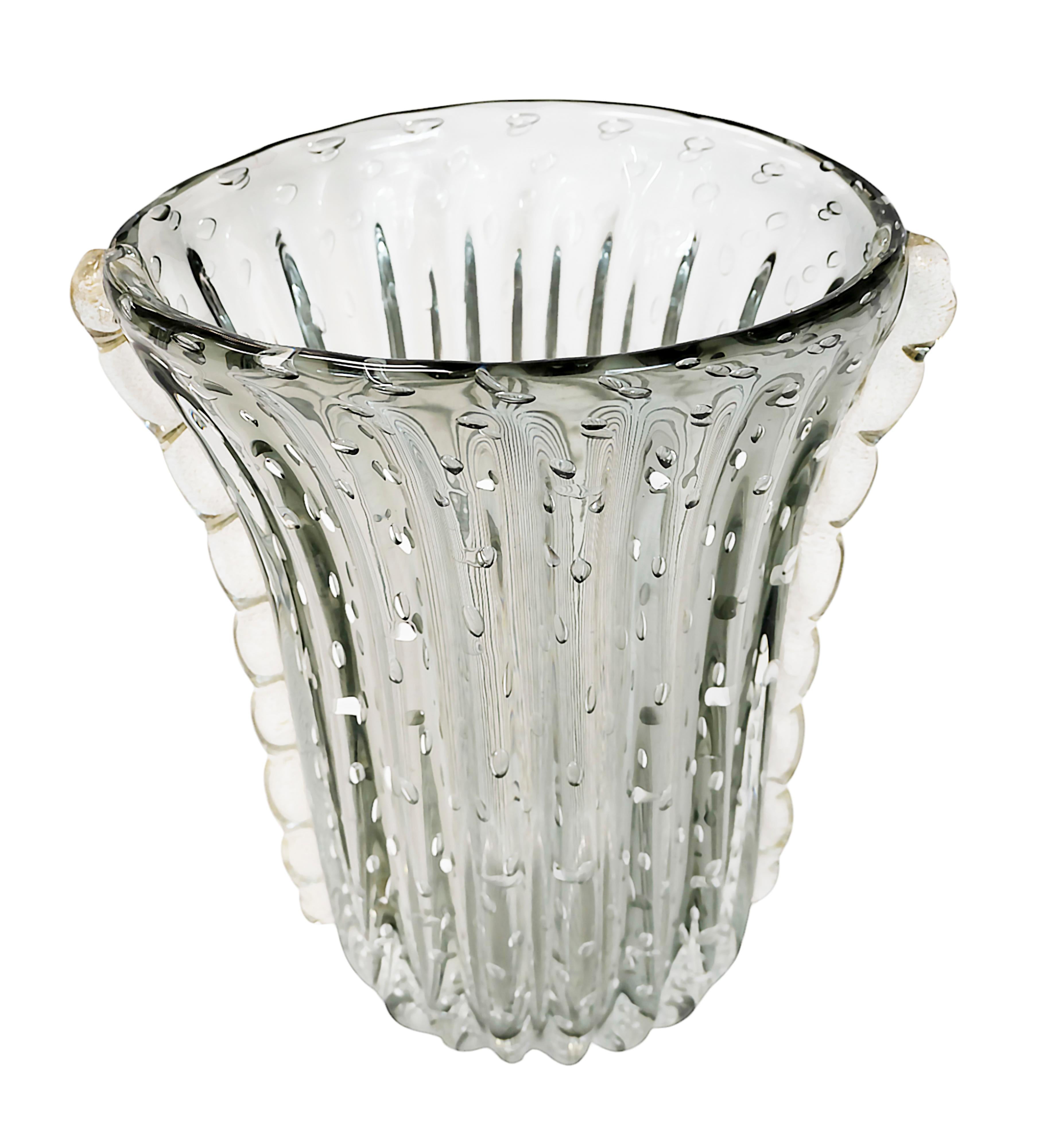 Handgefertigte italienische Vase aus Murano-Glas, ca. 1980er Jahre.
Das Glas ist von durchsichtiger grauer Farbe mit Luftblasen im Inneren.
Die Seiten sind mit eingelegten Goldstaub-Glasdetails verziert.
Sehr guter/exzellenter Zustand.