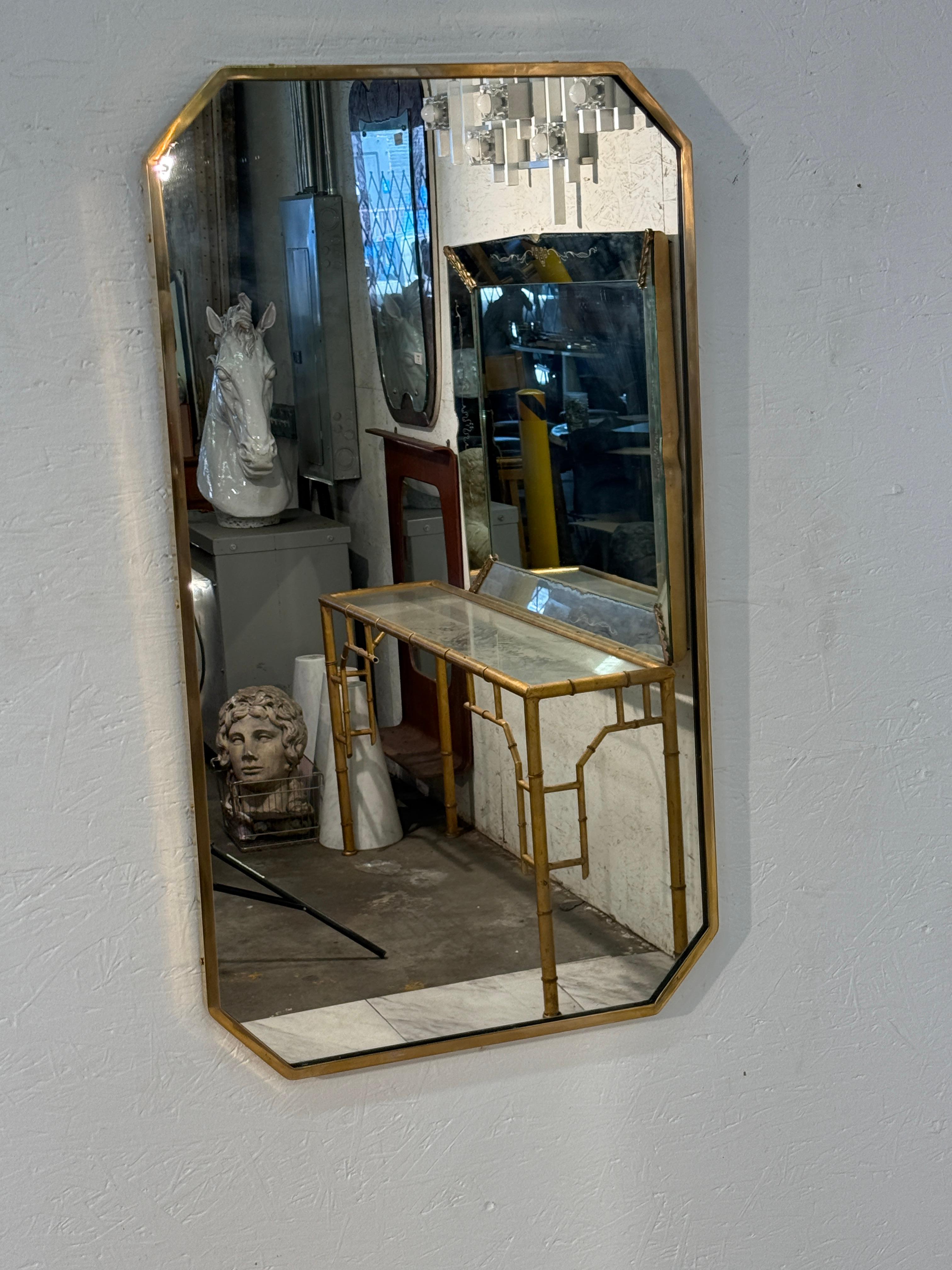 A stylish Italian mid-century rectangular wall mirror framed in slim brass with elegantly beveled corners. Its clean geometry and warm metallic finish capture the refined craftsmanship of Italian design, balancing simplicity with subtle