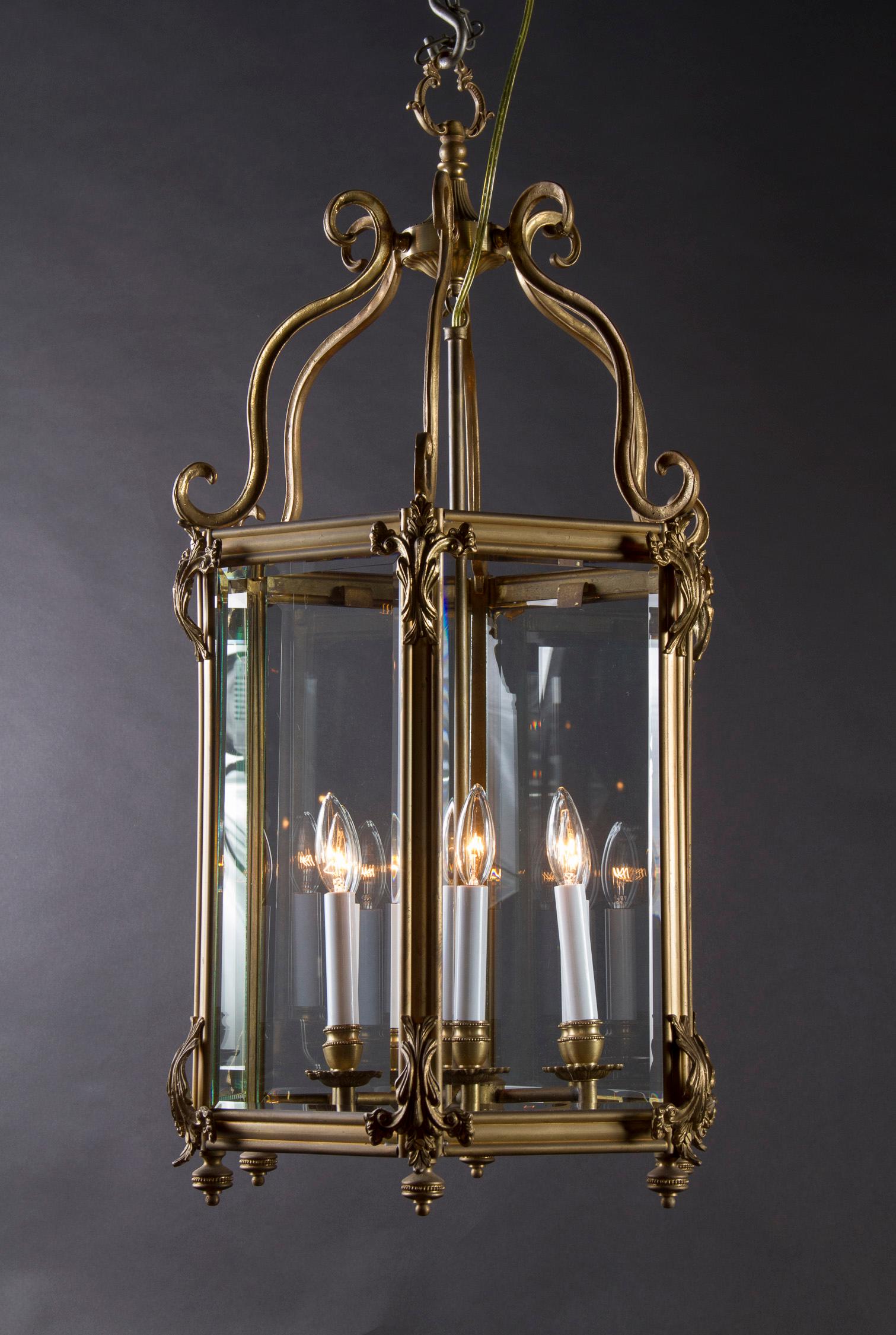 This beautiful bronze lantern features six bevelled glass panes and is adorned with patterned finials at all six corners of the fixture's bottom. The vintage Italian piece dates back to the mid 20th Century and is suspended from the top by 6
