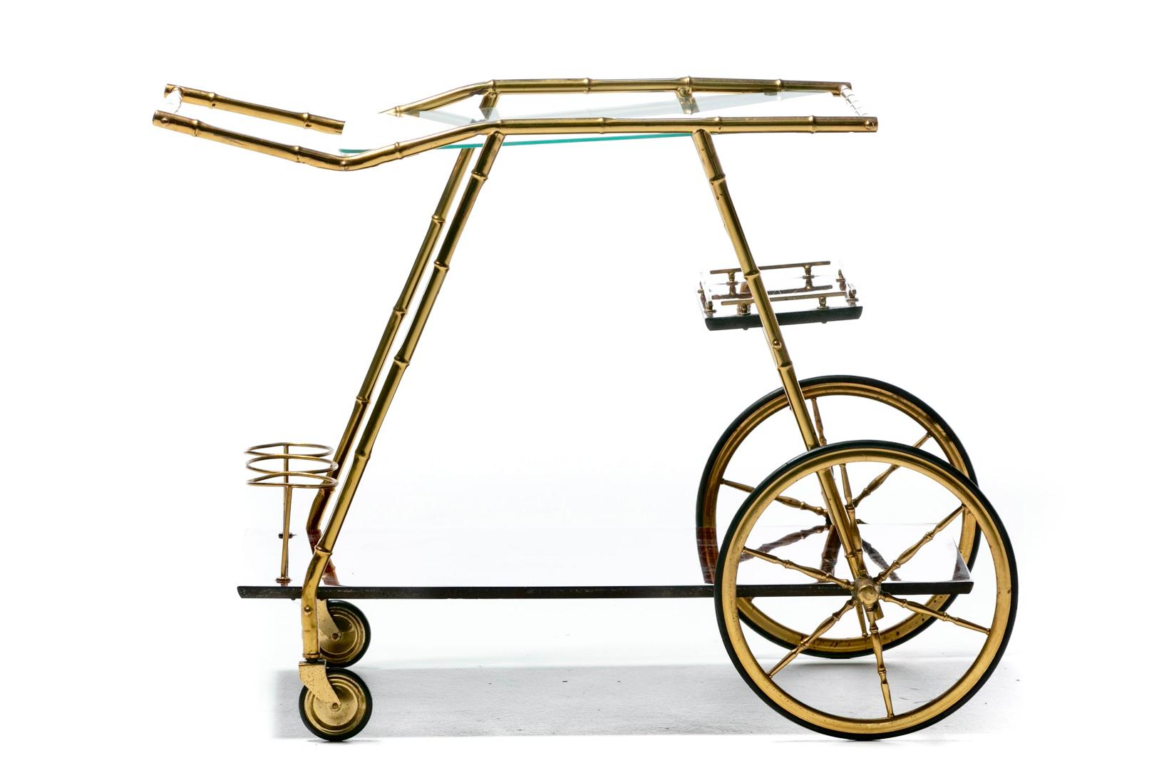 Roll into cocktail hour in style with this chic Italian Hollywood Regency brass bar cart. The details. Brass frame with faux bamboo detailing. Glass top shelf is perfect for displaying a sexy set of cocktail glasses and cleans up easily while