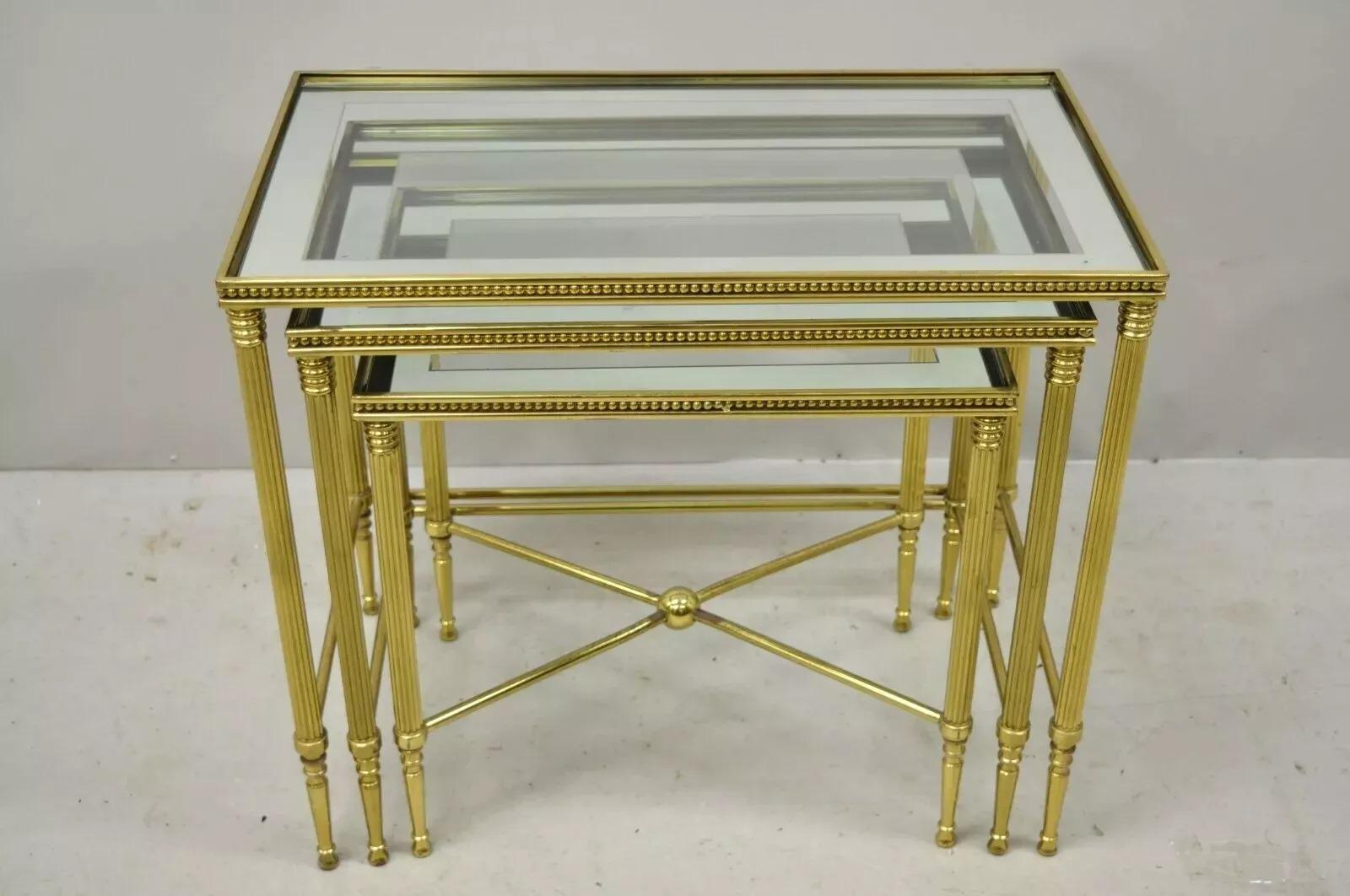 Vintage Italian Hollywood Regency Brass Mirror Glass Top Nesting Side Tables - Set of 3. Item features glass tops with mirror borders, brass beaded trim, ball form stretcher, brass construction, sleek tapered legs, quality Italian craftsmanship.