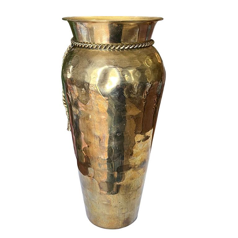 A beautiful Hollywood Regency Mid-Century Modern brass Trompe L'oeil ribbon vase. This lovely urn is created from brass and is decorated with faux ribbon and tassels around the neck. 

This vessel would be fabulous on a small table, or nightstand