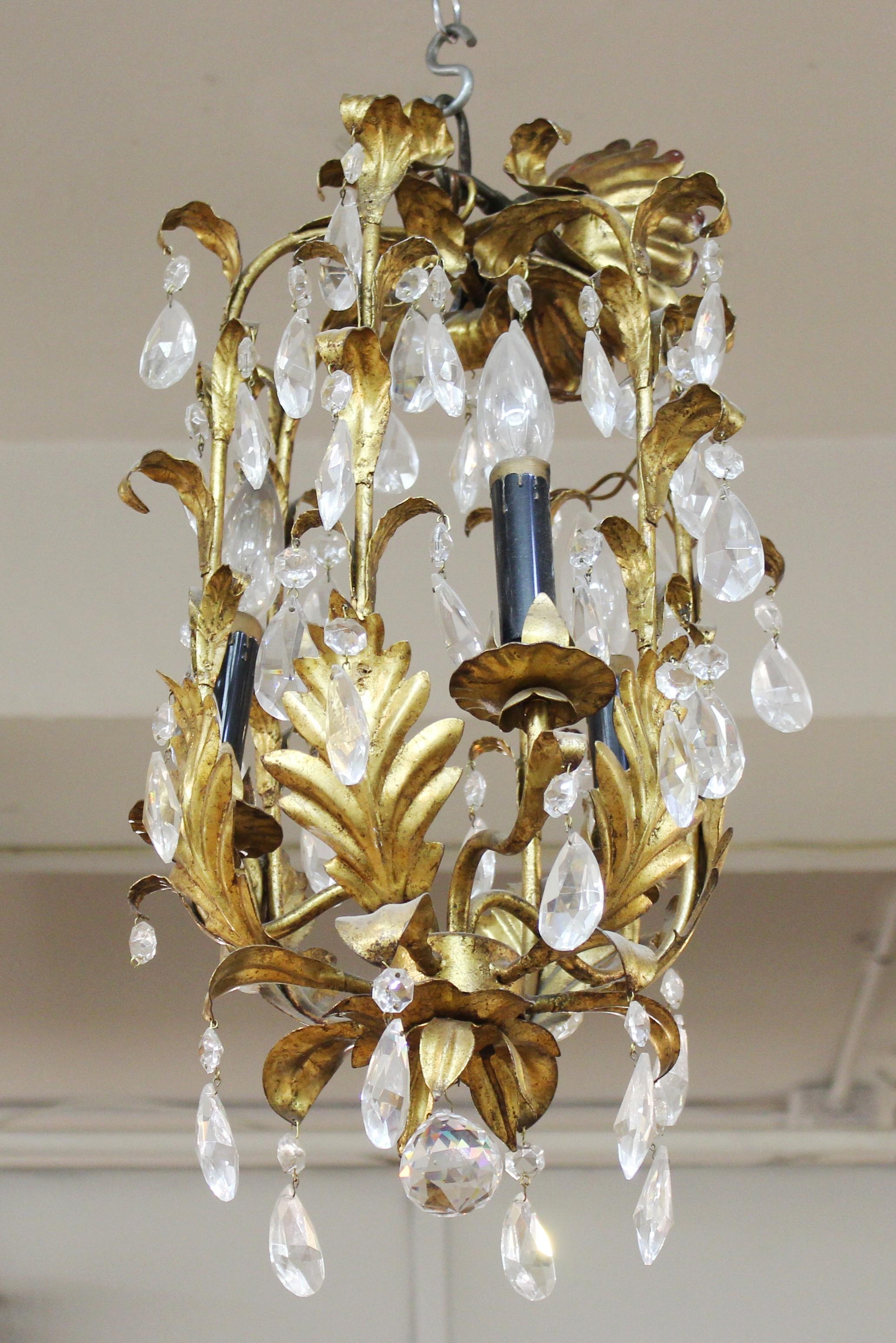 Italian Hollywood Regency style diminutive chandelier with gilt tole foliage elements and crystal droplets.