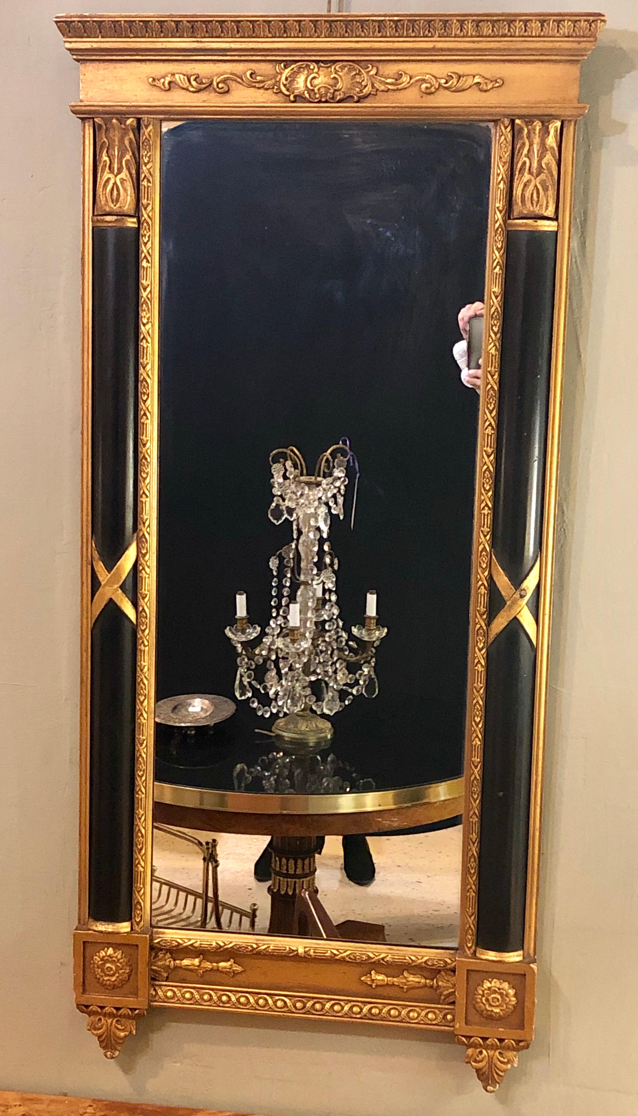 Italian Hollywood Regency ebony and gilt decorated wall or console mirror in the style of Maison Jansen. This mirror has a rectangular form with rosettes and an X-design modern carvings. The mirror would look stunning over an ebony commode or