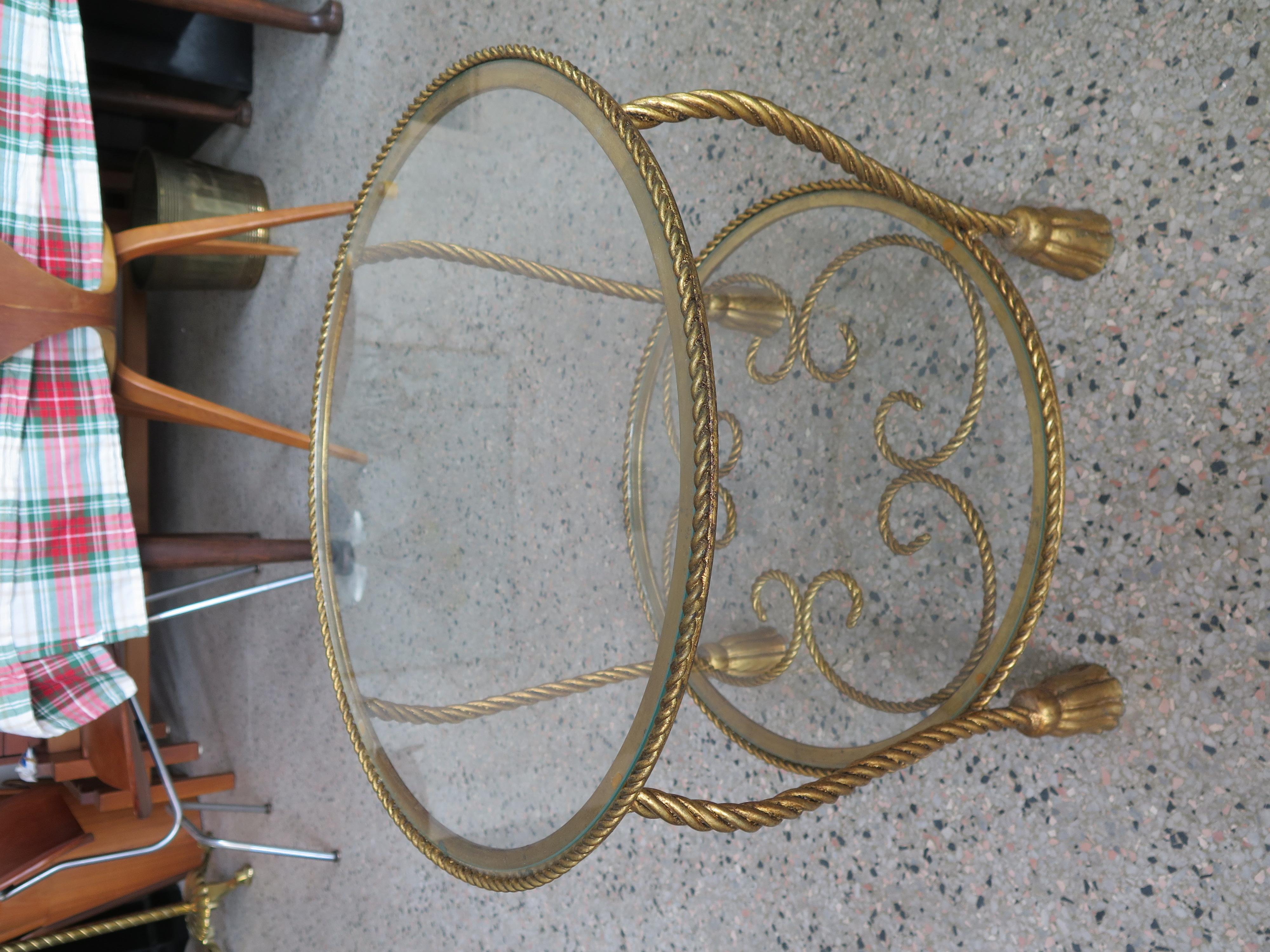 An elegant and practical two tier Italian gilt metal rope and tassel table. Measures 21'd and 17.25