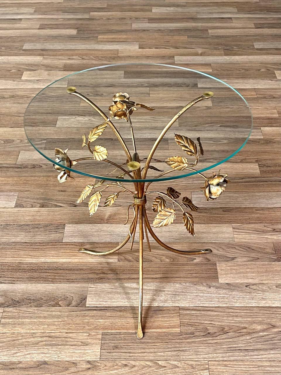 Condit : Condition Vintage Originale

Matériaux : Métal doré, plateau en verre original

Cette charmante table d'appoint capture le charme romantique du design Hollywood Regency avec sa base sculptée en métal doré qui s'épanouit en roses et en