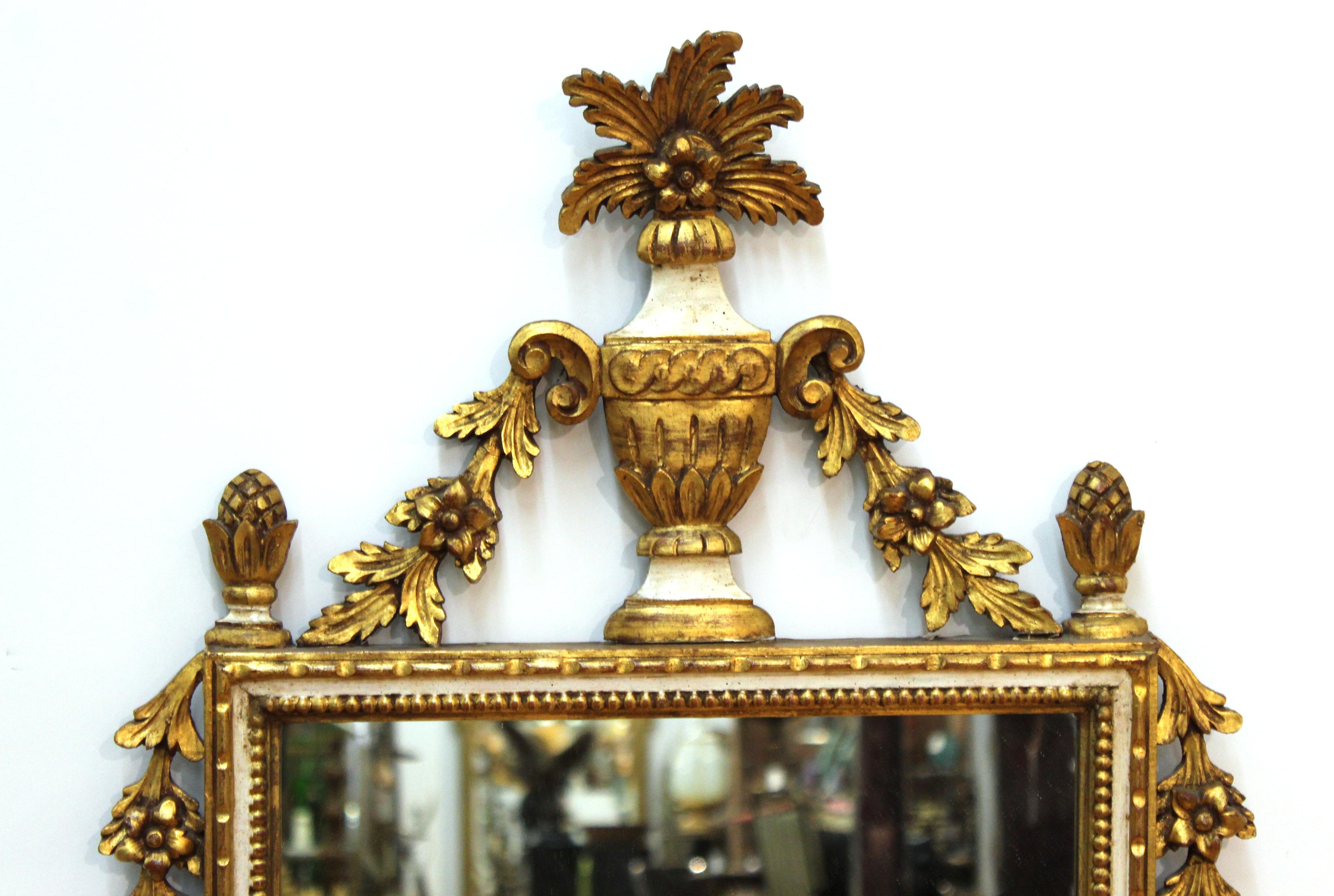 Italian Hollywood Regency partially gilt and painted carved wood wall mirror in neoclassical Revival style.