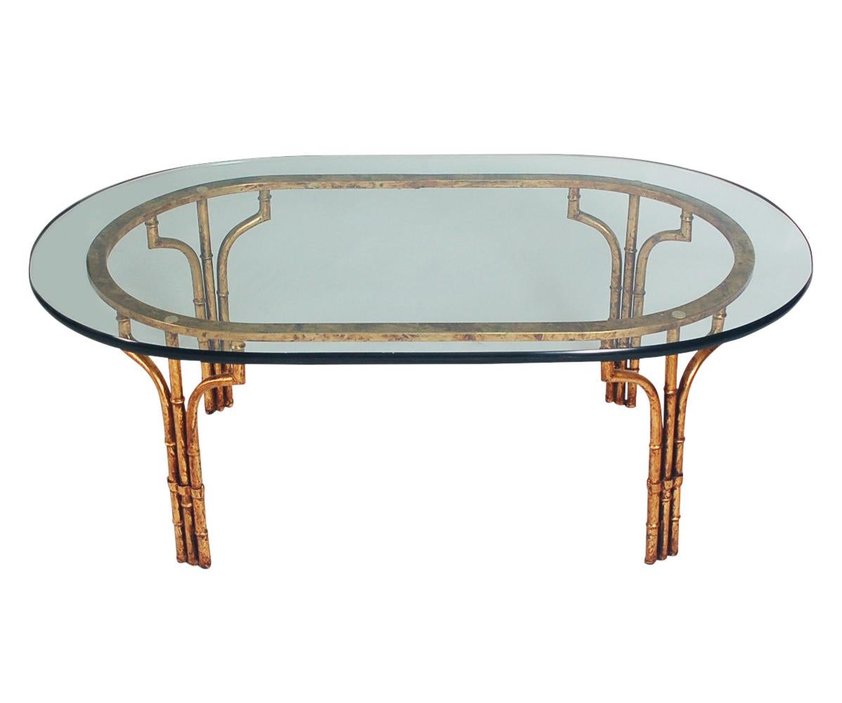 A classy and glamorous coffee table made in Italy in the 1960's . It features a gold gilded metal base with thick clear glass oval top.