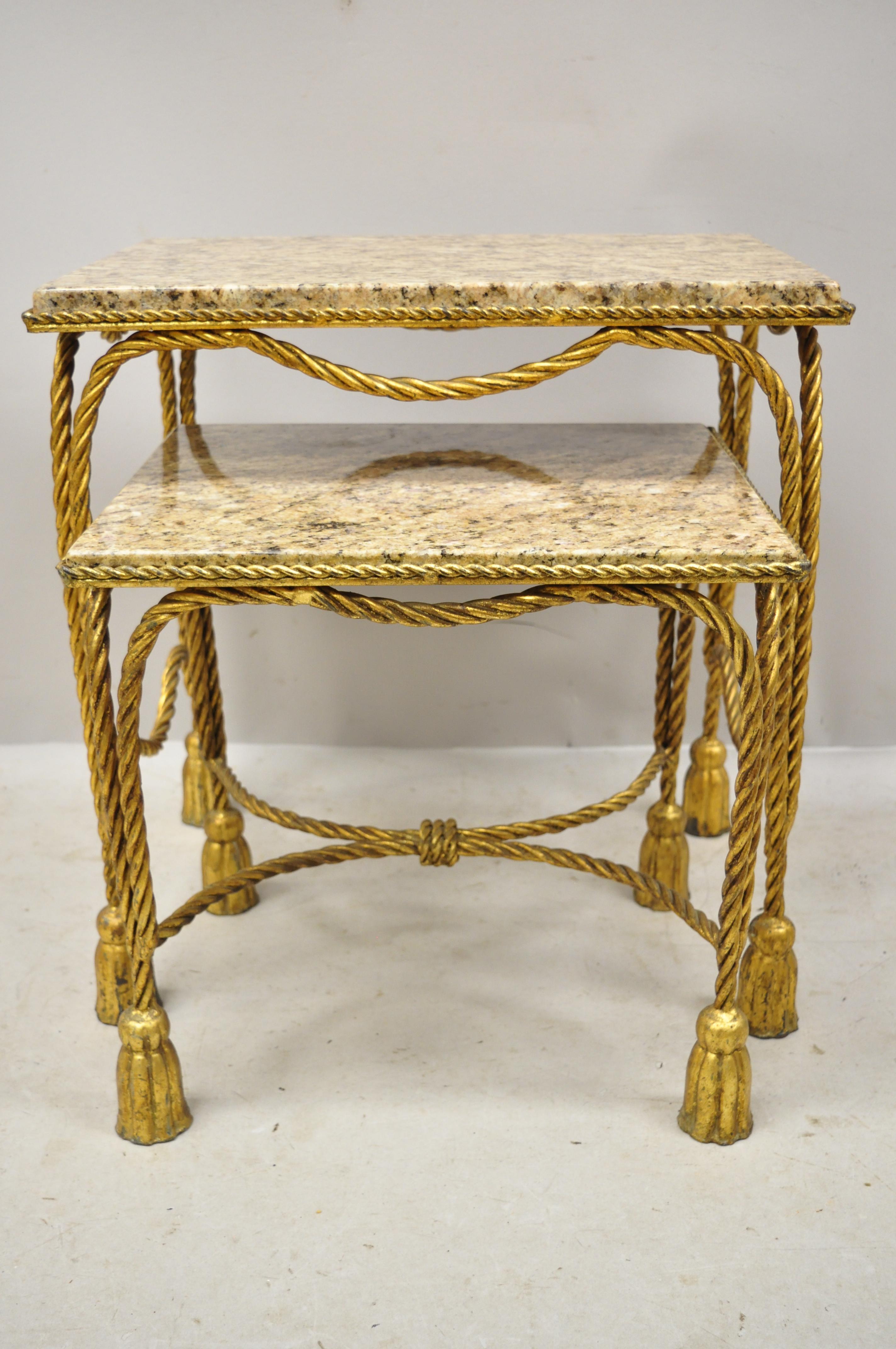 Mid-20th century Italian Hollywood Regency gold gilt iron rope tassel marble top nesting tables. Item features gold gilt iron bases, inset marble tops, rope and tassel design (2) nesting tables, very nice vintage item, great style and form, circa