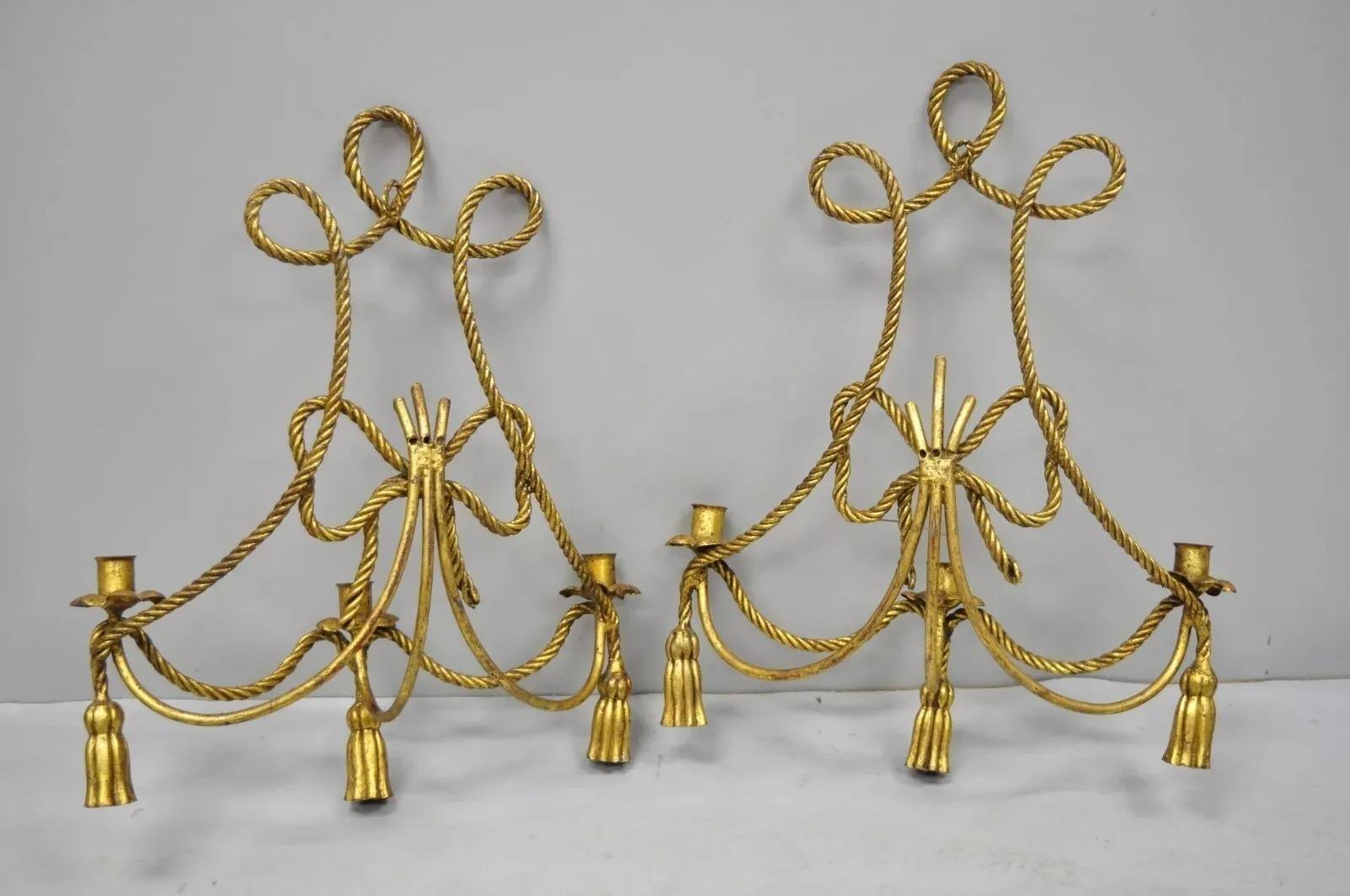 Paire d'appliques murales à houppes en corde dorée de style Hollywood Regency italien. Cet article se caractérise par une finition dorée, une construction en fer, des cadres uniques en forme de corde, de glands et de nœuds, 3 bougeoirs chacun, un
