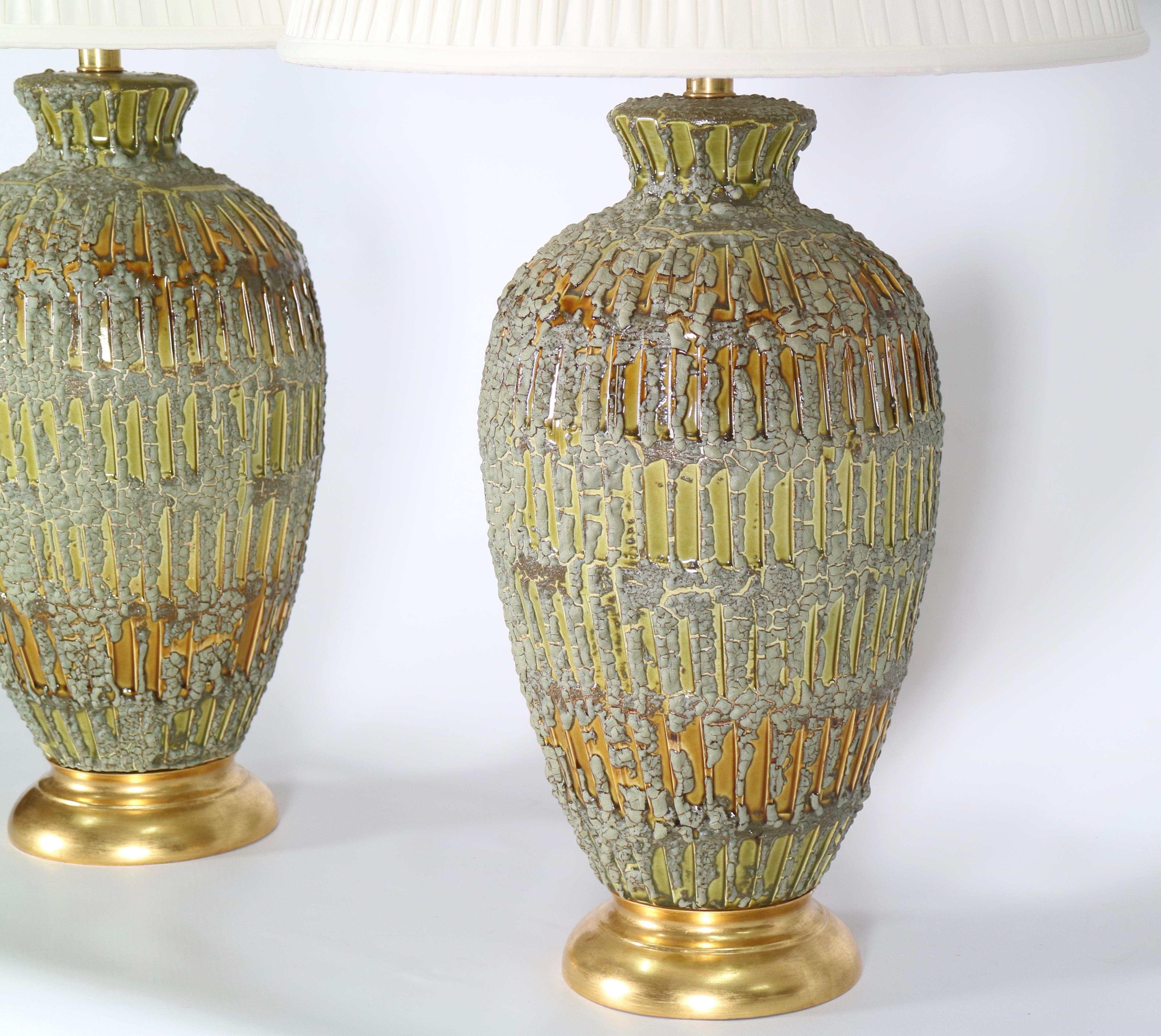 Italian Hollywood Regency ceramic lamps with a textured drip glaze in green and gold tones. Each is mounted to a gilded wooden base. These lamps date from the 1950s and are in excellent vintage condition having wear consistent with age and use.