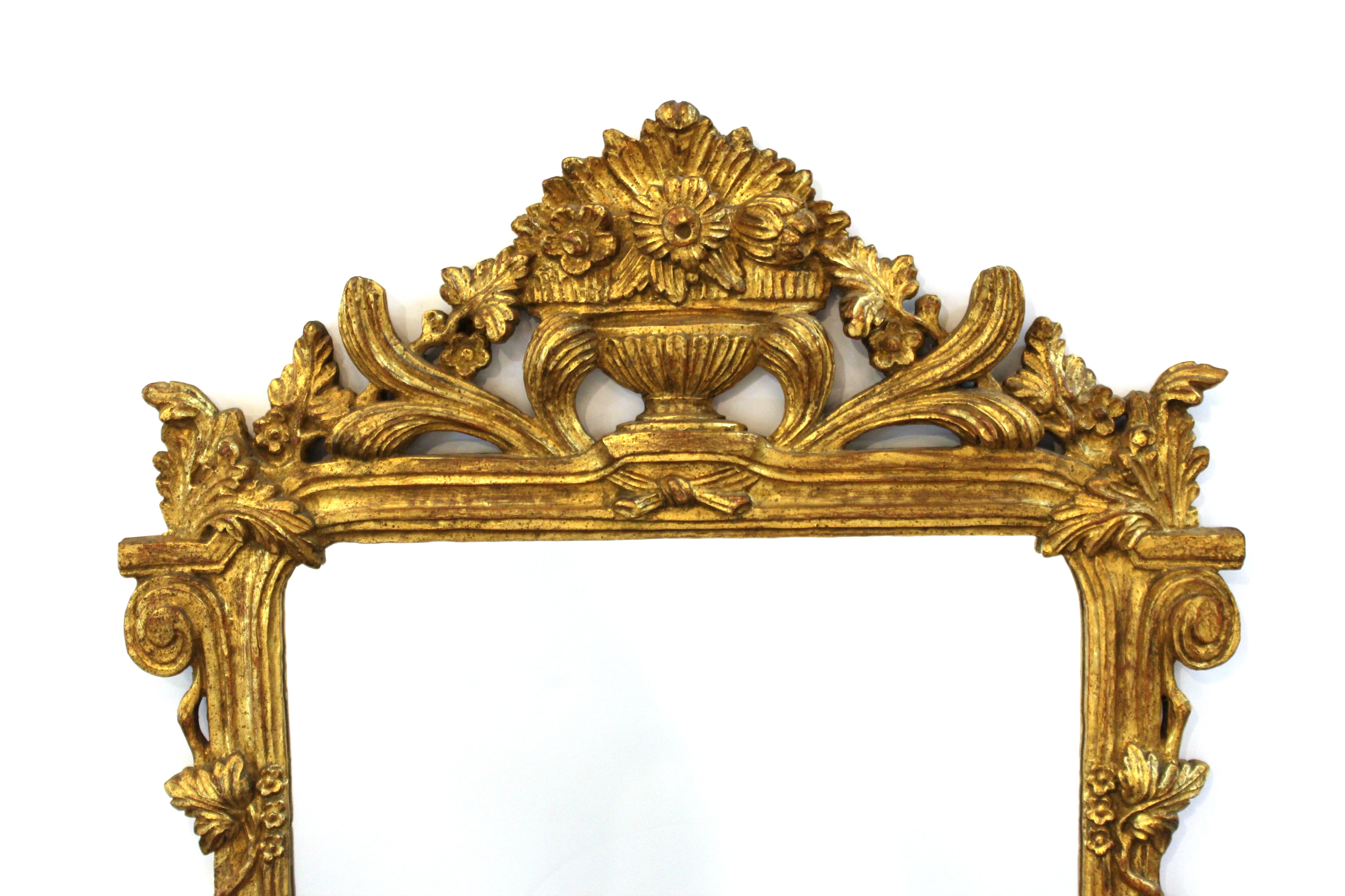 Italian Hollywood Regency mirror with elaborately carved neoclassical revival style gilt frame. The piece has a label on the back marked 'Made In Italy' and is in great vintage condition with age-appropriate wear.
