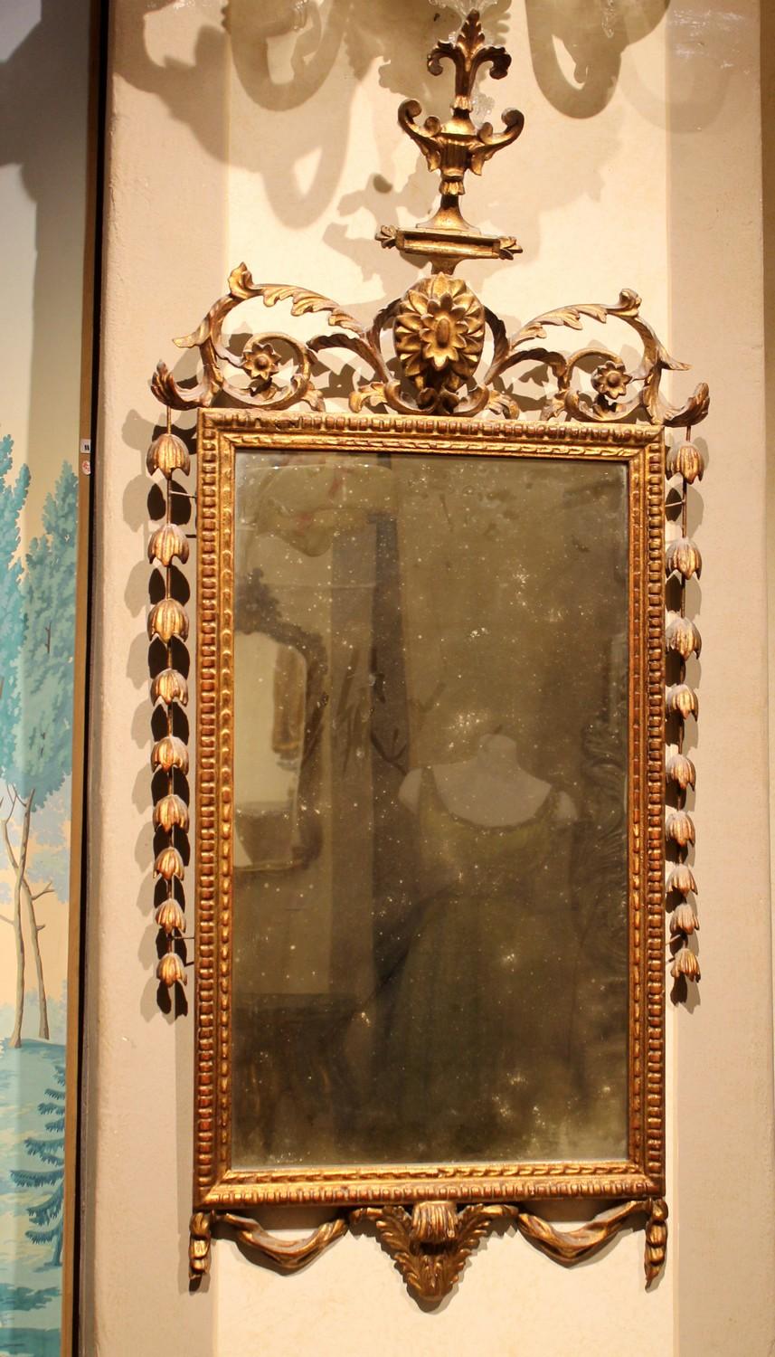 A fine Italian early 20th century giltwood rectangular swag mirror in Regency neoclassical style of narrow proportions and richly carved in a drapery style motif.
The rectangular mirror plate surmounted by pierced carvings featuring scrolls,
