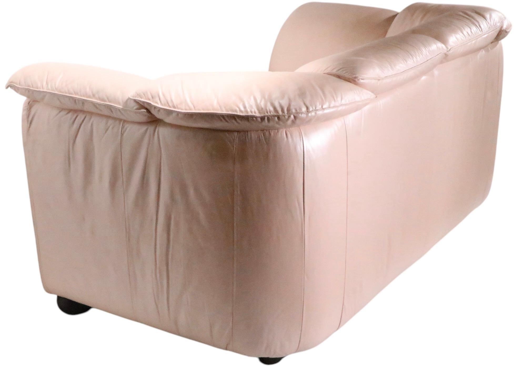 Voguish pearlized pink leather loveseat, made in Italy by Natuzzi Salotti Spa design attributed to Pierluigi Cerri, circa 1980/90's. In addition to its chic and sophisticated style, this exceptional sofa is extremely comfortable. This example is in