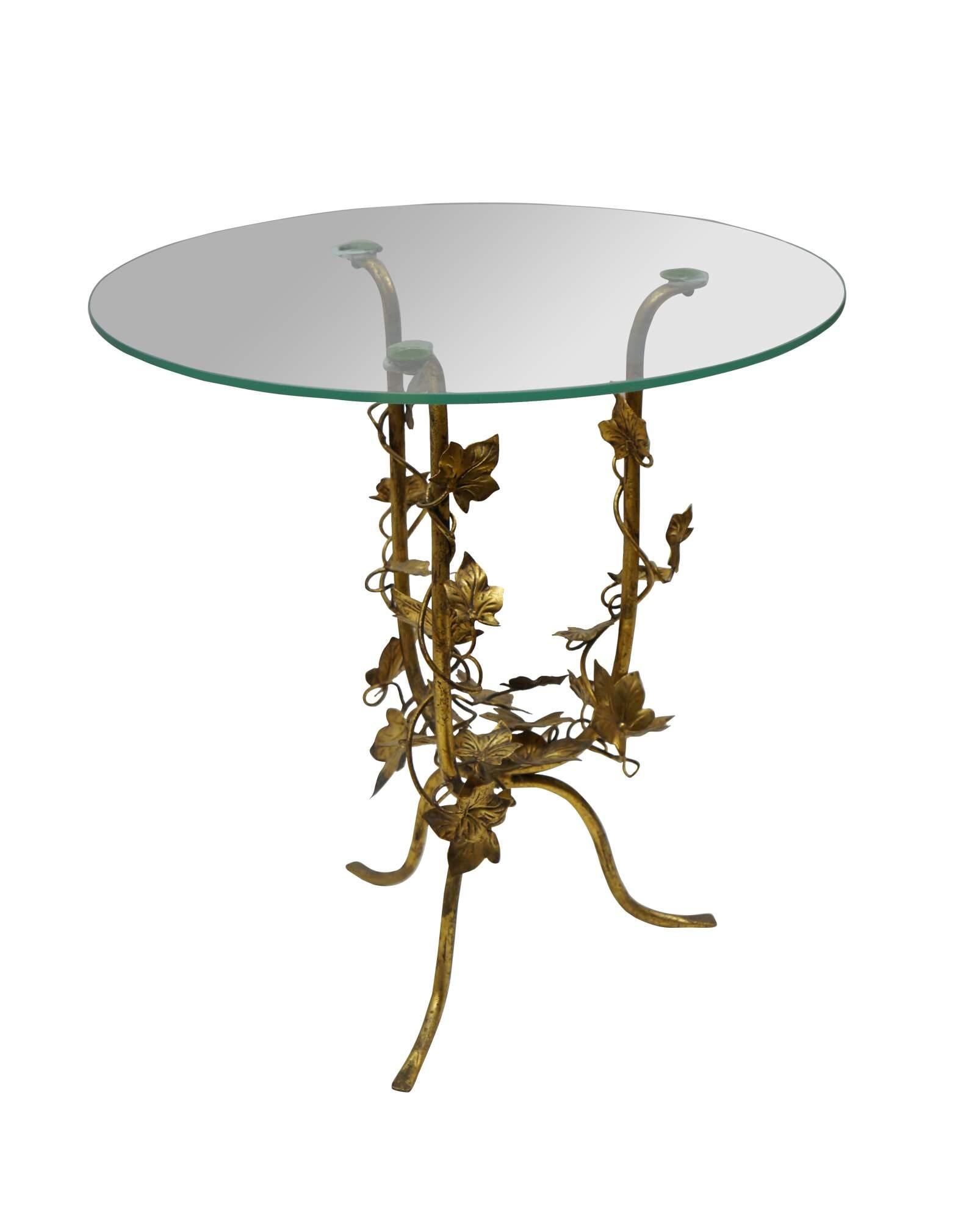 Vintage 20th century Hollywood Regency / Italian Florentine style side / end / accent table featuring a round glass top on a three leg gilt toleware base wrapped in vines of ivy leaves.