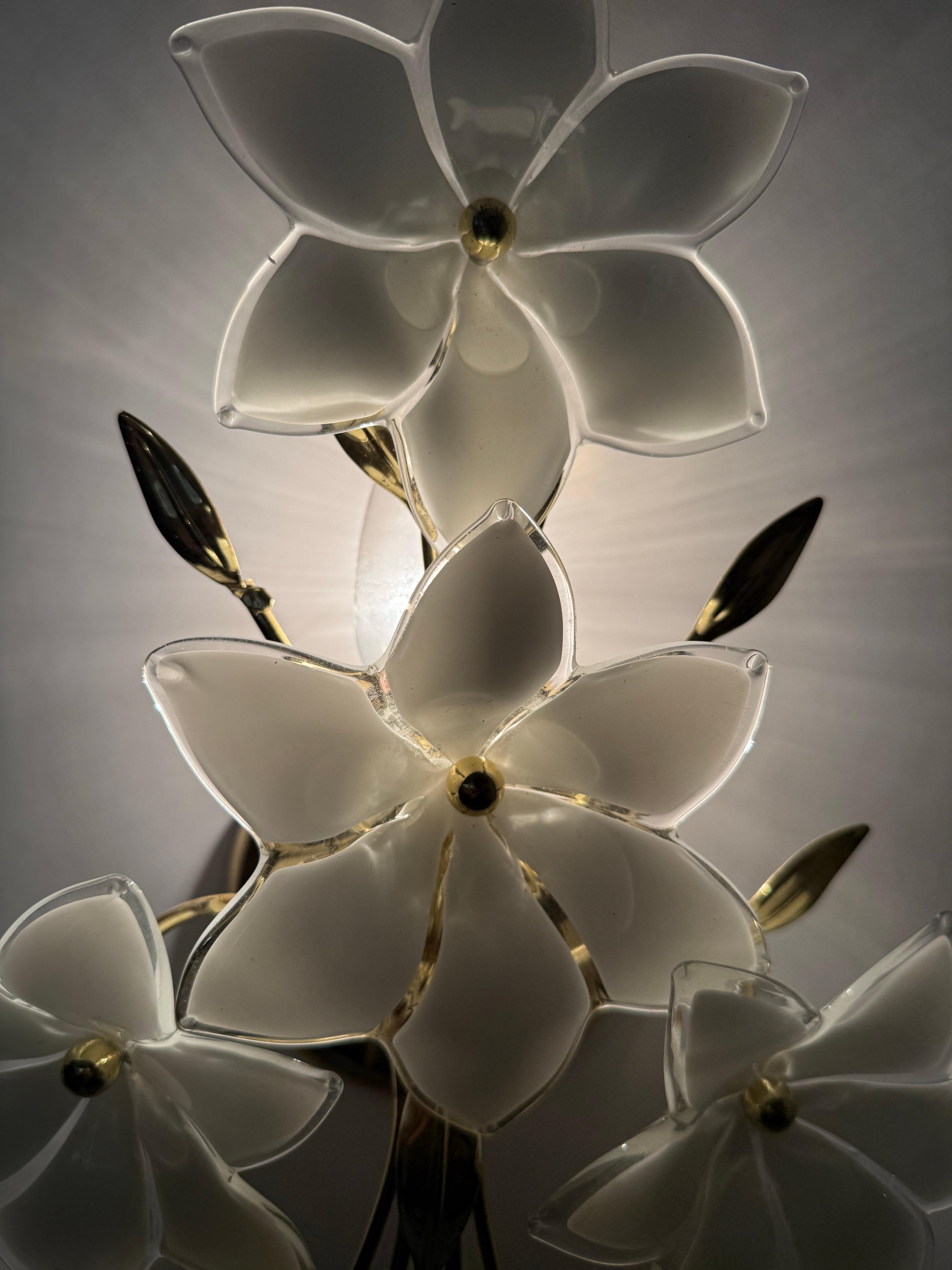 Este hermoso conjunto de dos apliques de pared cautiva con el encanto de su década. Los maestros sopladores de vidrio dieron forma a mano a las hermosas flores de cristal, haciendo que cada flor de cristal fuera única. El marco metálico dorado con