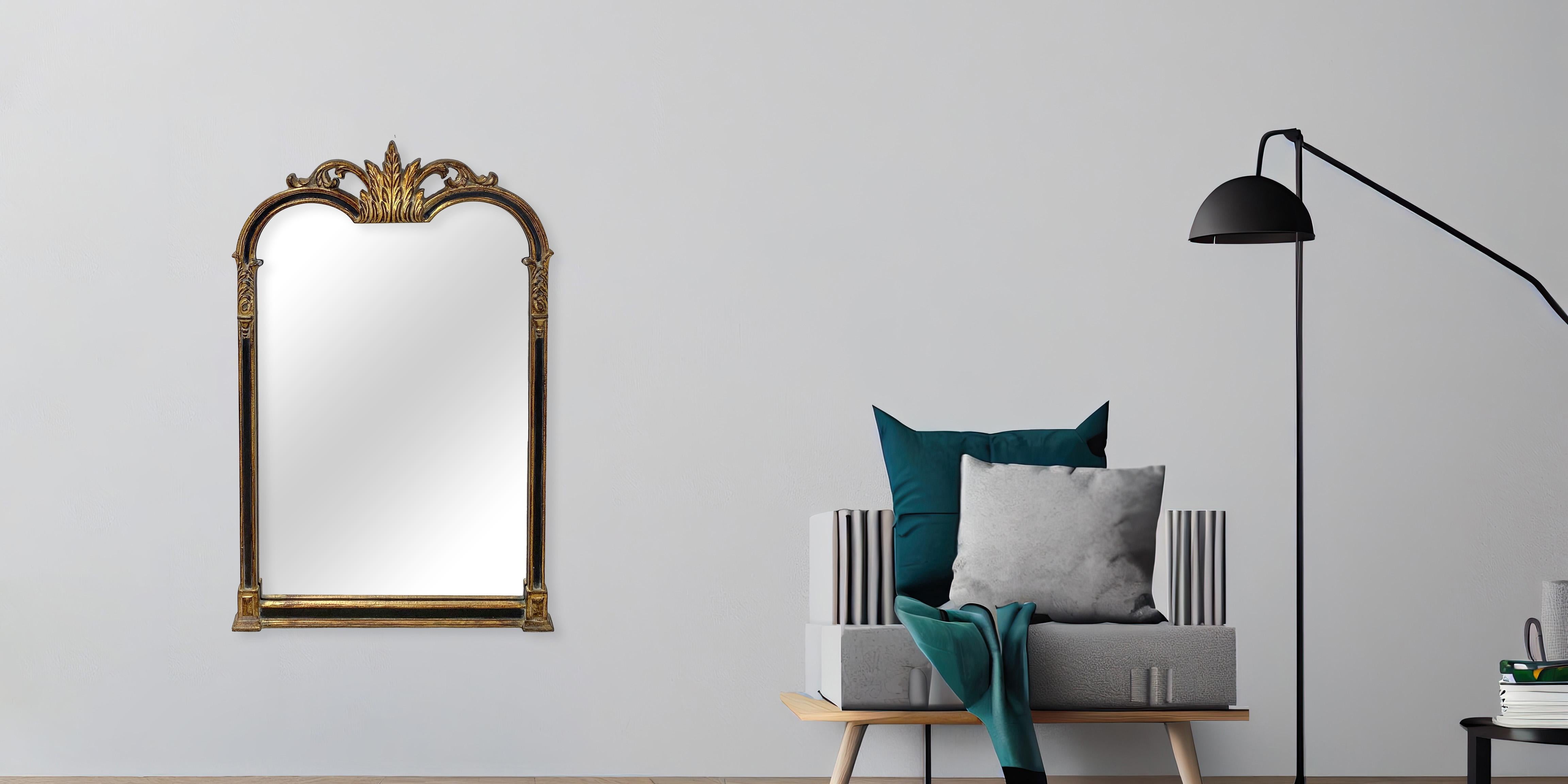An Italian Hollywood Regency style  black and gilt mirror wall, mantel or table mirror by Friedman Brothers. Adorned with a captivating finish of black and gold leaf, this mirror is a testament to timeless elegance. The high-quality carved wood is