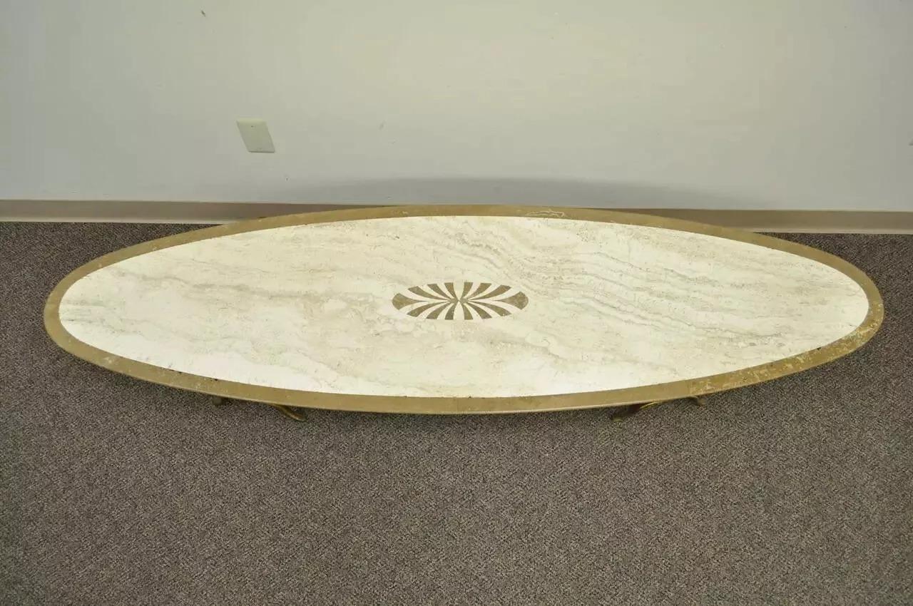 Table basse ovale en travertin et laiton pour planche de surf. L'objet présente un plateau en travertin incrusté d'une roue d'épingle et quatre pieds sculpturaux en laiton massif de forme x. Le designer n'est pas confirmé, mais le style est