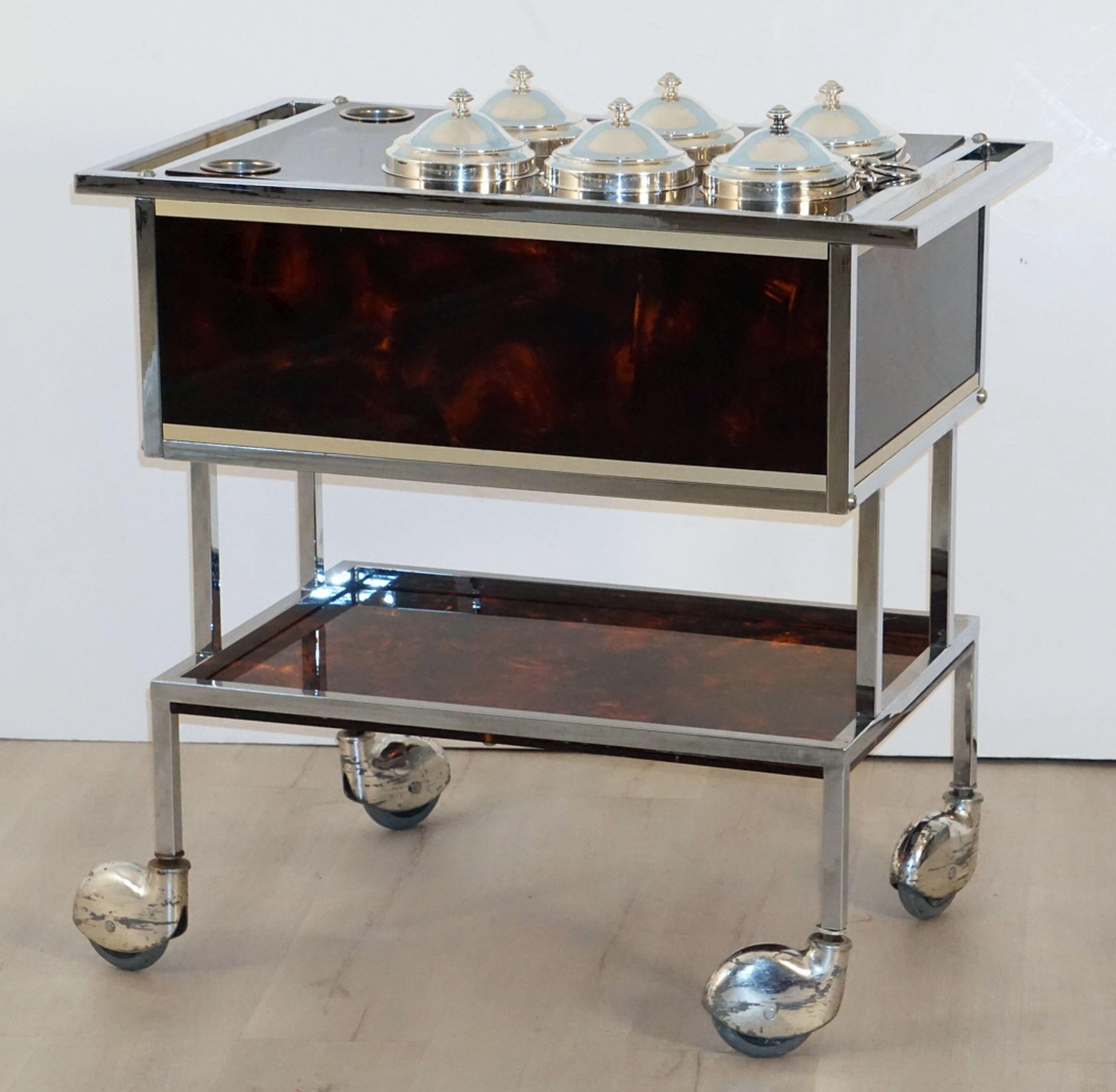 A fine Italian ice cream cart of chrome and faux tortoise shell, featuring a rectangular body with handle and six compartments with removable covered lids, two slots for ice cream scoops, a lower shelf, and set upon rolling casters.

Height with