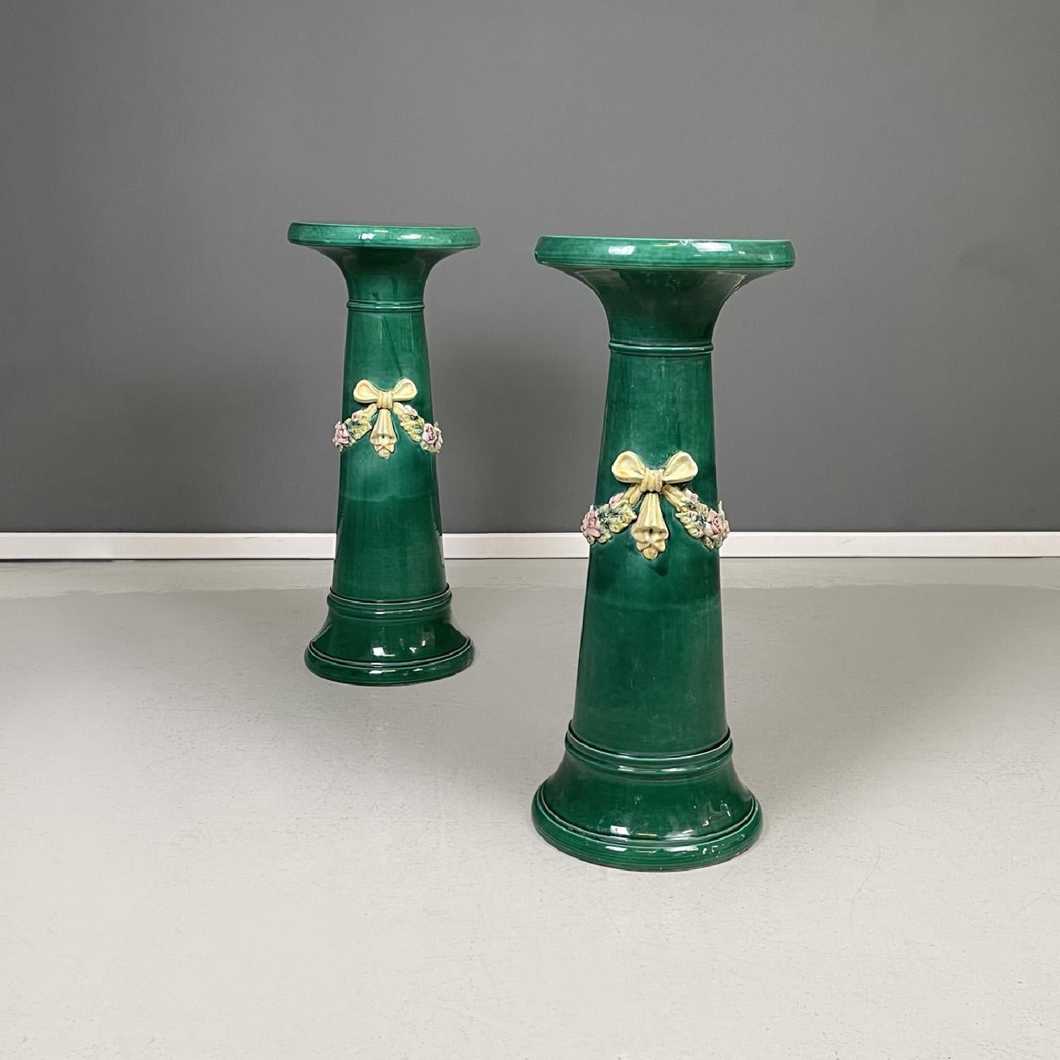 Italian imperial style green ceramic columns pedestals bows and flowers, 1930s
Pair of pedestals with a round base. The tapered structure narrows at the top and then widens at the base. The structure is in green ceramic with a glossy finish, in the