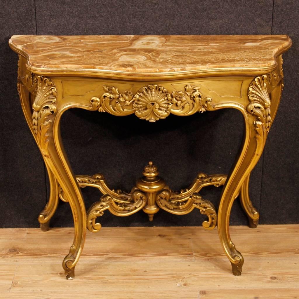 Italian console from mid-20th century. Furniture in wood and plaster richly carved and gilded of pleasant decor. Top in original onyx that presents a conservative restoration intervention now in fair condition. Console table supported by four carved