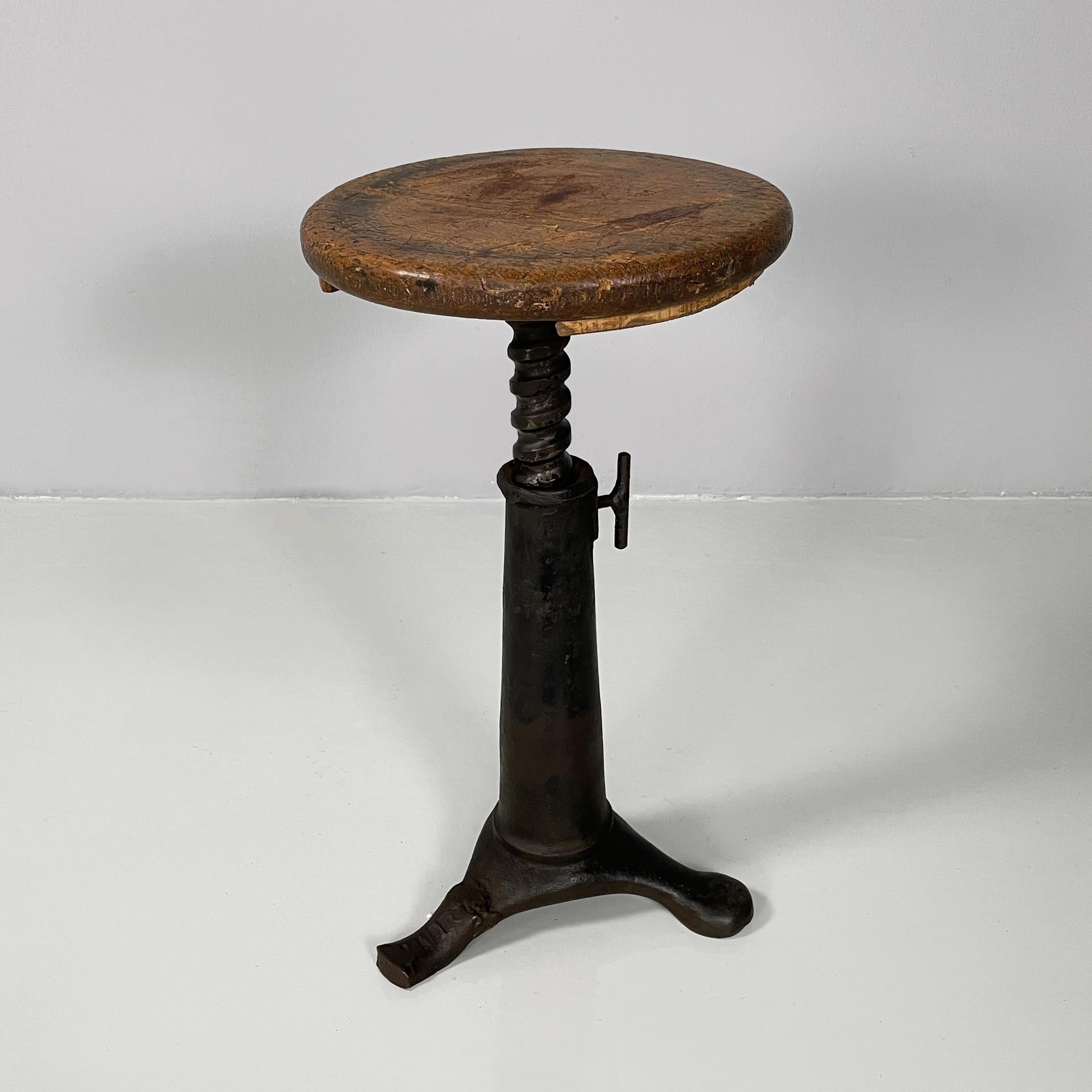 Italian industrial round stool in cast iron and wood, 1930s 
Stool with round wooden seat. The seat is adjustable in height. Cast iron conical base with three legs, two have square sections and one rounded.
1930s
Vintage condition. The wood has