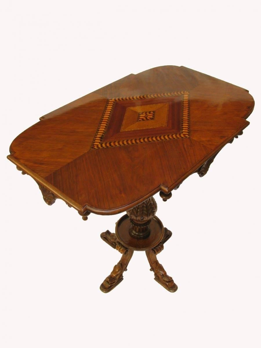 A 20th century Italian centre table with rectangular shaped walnut veneered top decorated with an elegant central walnut, maple and ebonized pear wood geometric design inlay. A molding on apron below the top, with pinnacles and ornamental shell