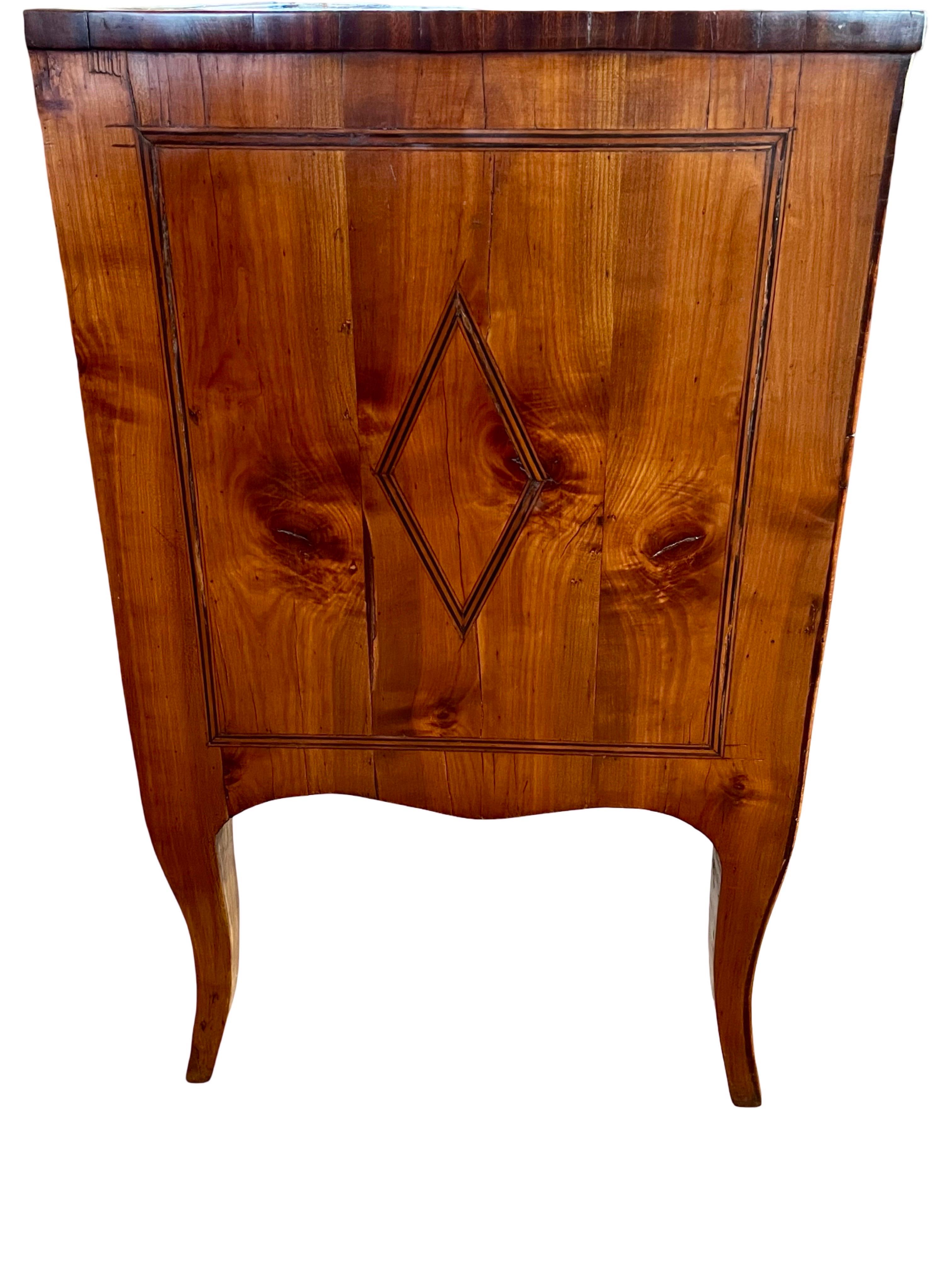 Cassettiera realizzata a mano in Italia all'inizio del 1800 con ciliegio e decorata con intarsi in noce. La commode presenta due cassetti sovrapposti con bordi ogee, entrambi con splendidi incastri a coda di rondine fatti a mano e decorazioni a