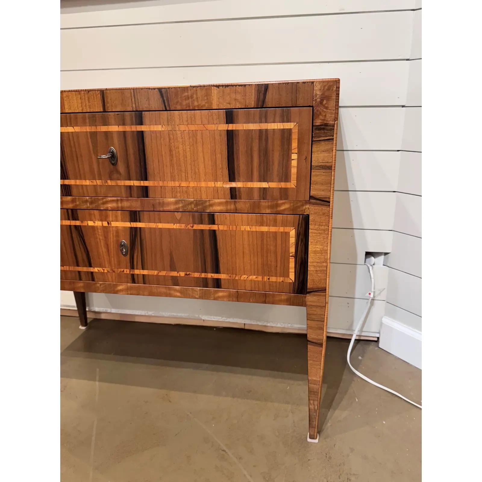 This stunning Italian veneer commode side table exudes timeless elegance with each chest featuring intricate wood inlays, showcasing exquisite artistry and attention to detail. The rich tones of the wood are beautifully complemented by the