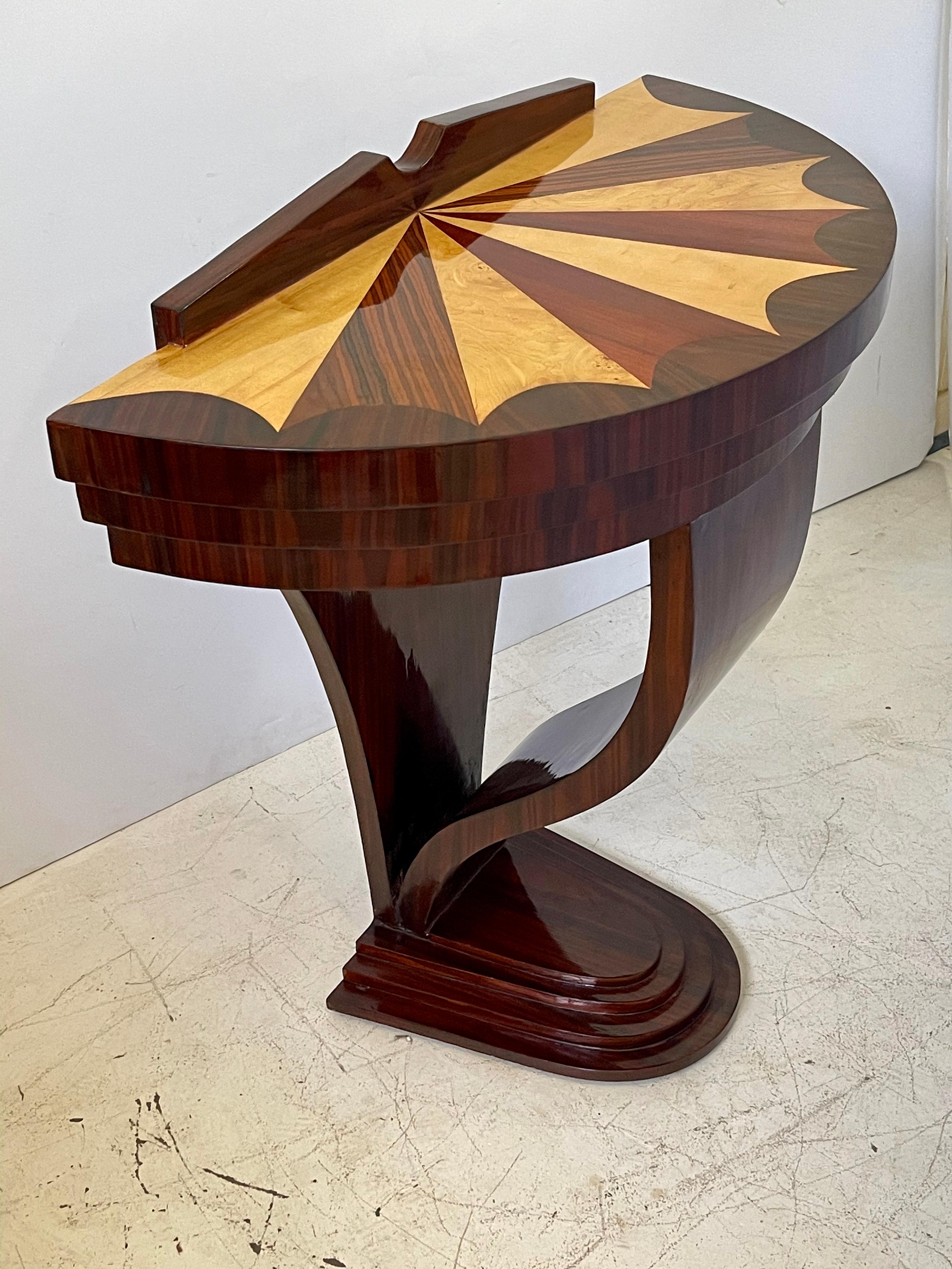 20th century Italian console table in the Art Deco style with a demilune shaped top with extraordinary veneer and fan inlay. The table’s frieze is recessed into three tiers over a tapered and downswept bentwood front leg that terminates into a
