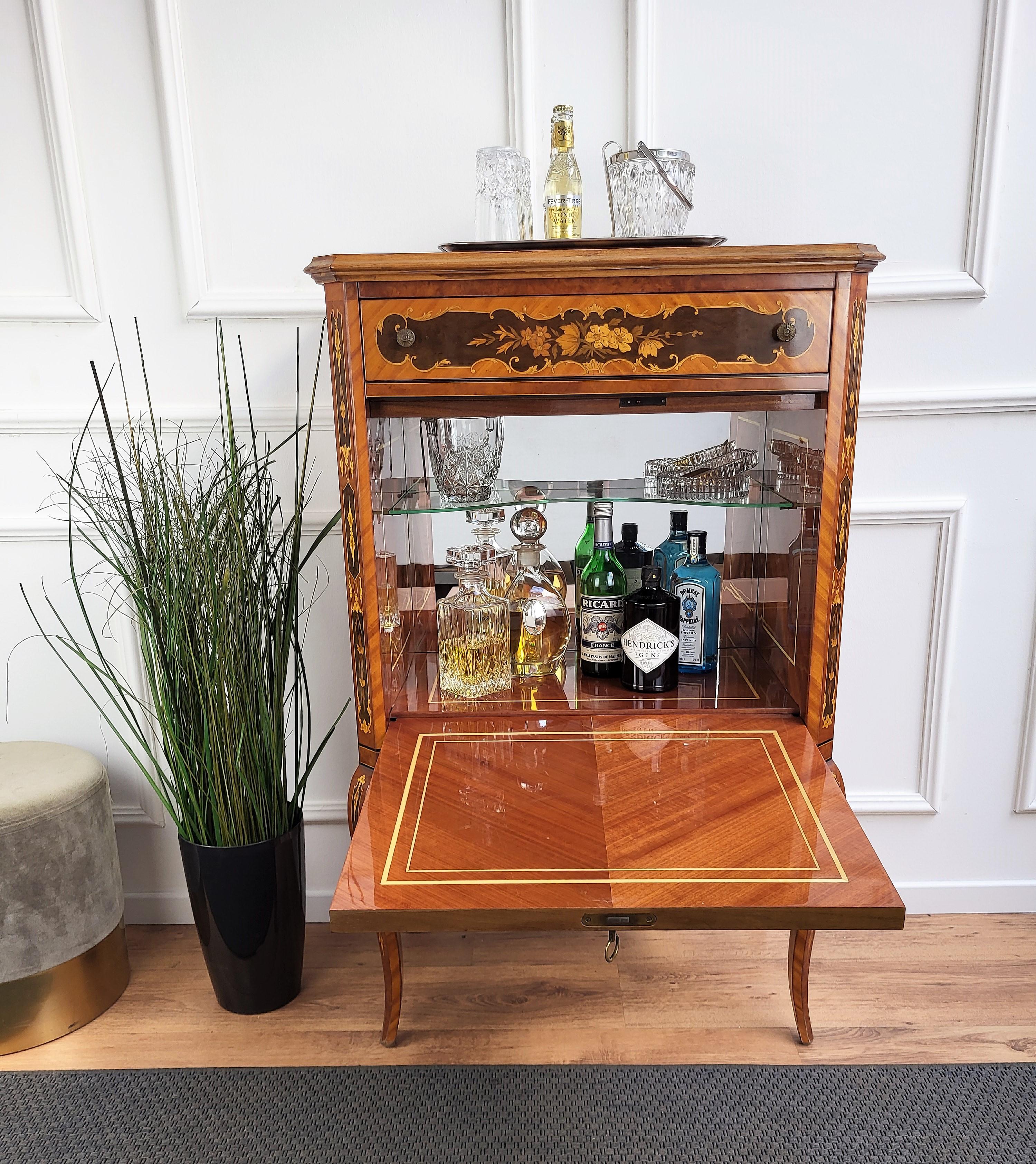 Very elegant Italian dry bar cabinet with slant drop front, with the beautiful light and dark wood inlay decors in classic figures all around the piece and a top and bottom drawers. When opened in the central part we find the mirror decorated dry