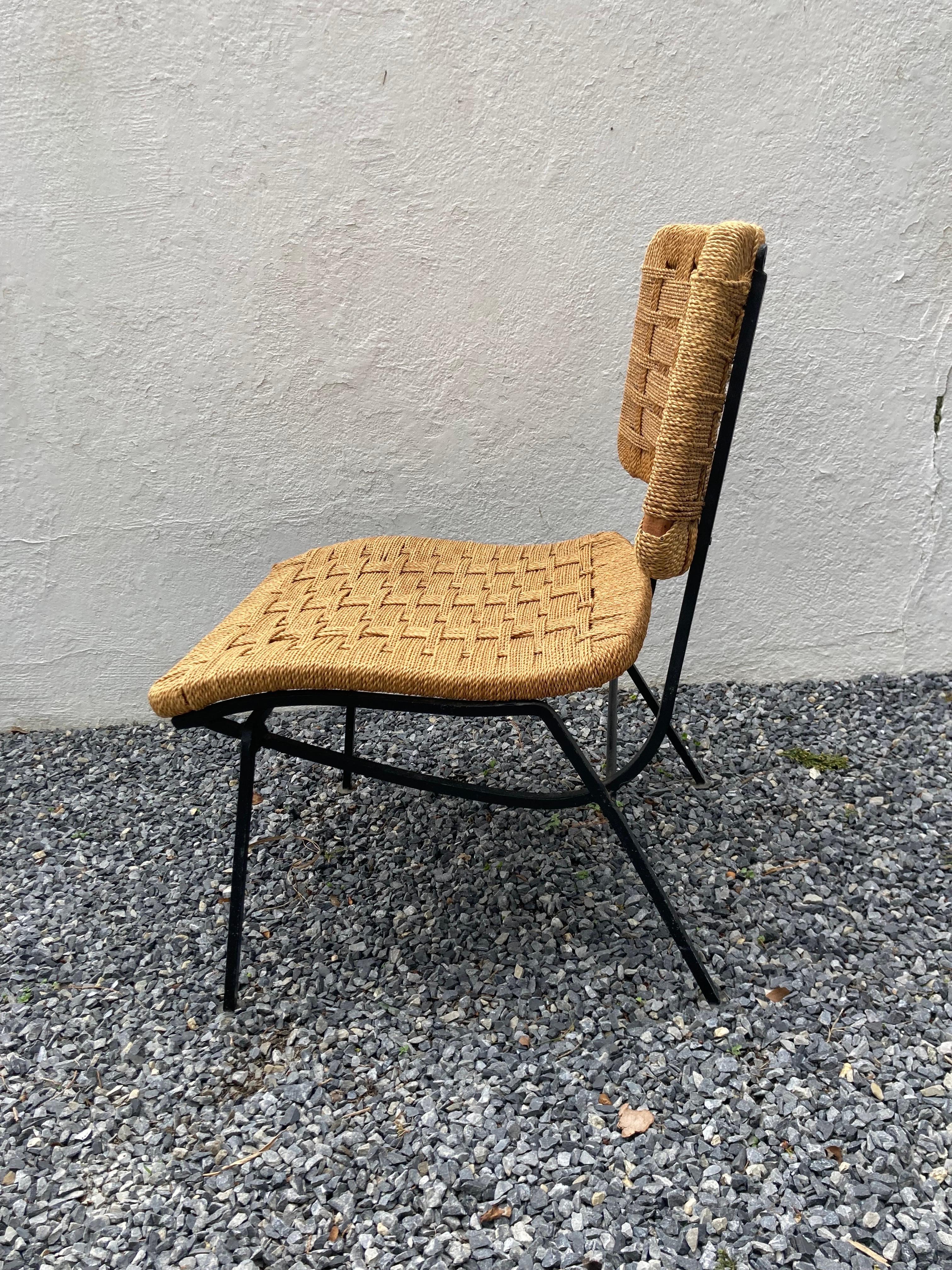 Iron framed chair with woven rope seat and back.
