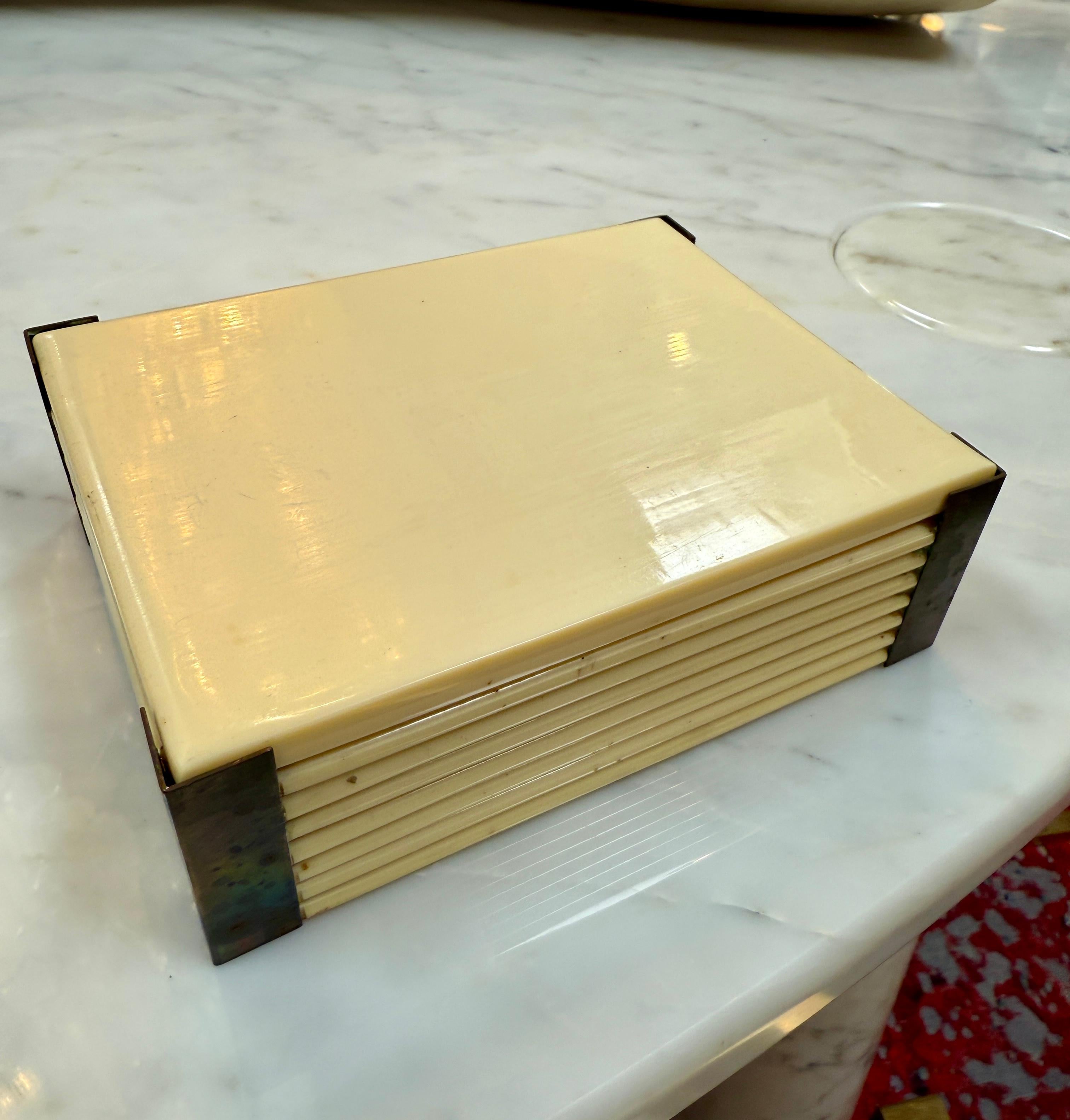 Boîte décorative italienne sophistiquée des années 1970, avec un corps laqué crème, des détails nervurés et des accents de coin en laiton. La forme rectangulaire épurée souligne l'élégance raffinée du design italien du milieu du siècle, ce qui en