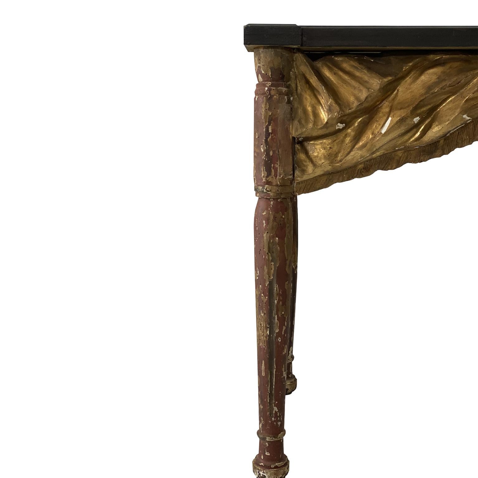 Stunning Italian constructed lacquered and gilded console with 18th and 19th century wood. With an ebony top and a red legs and a stunning gilded ribbon center. This is definitely a statement piece in modern and traditional homes alike.