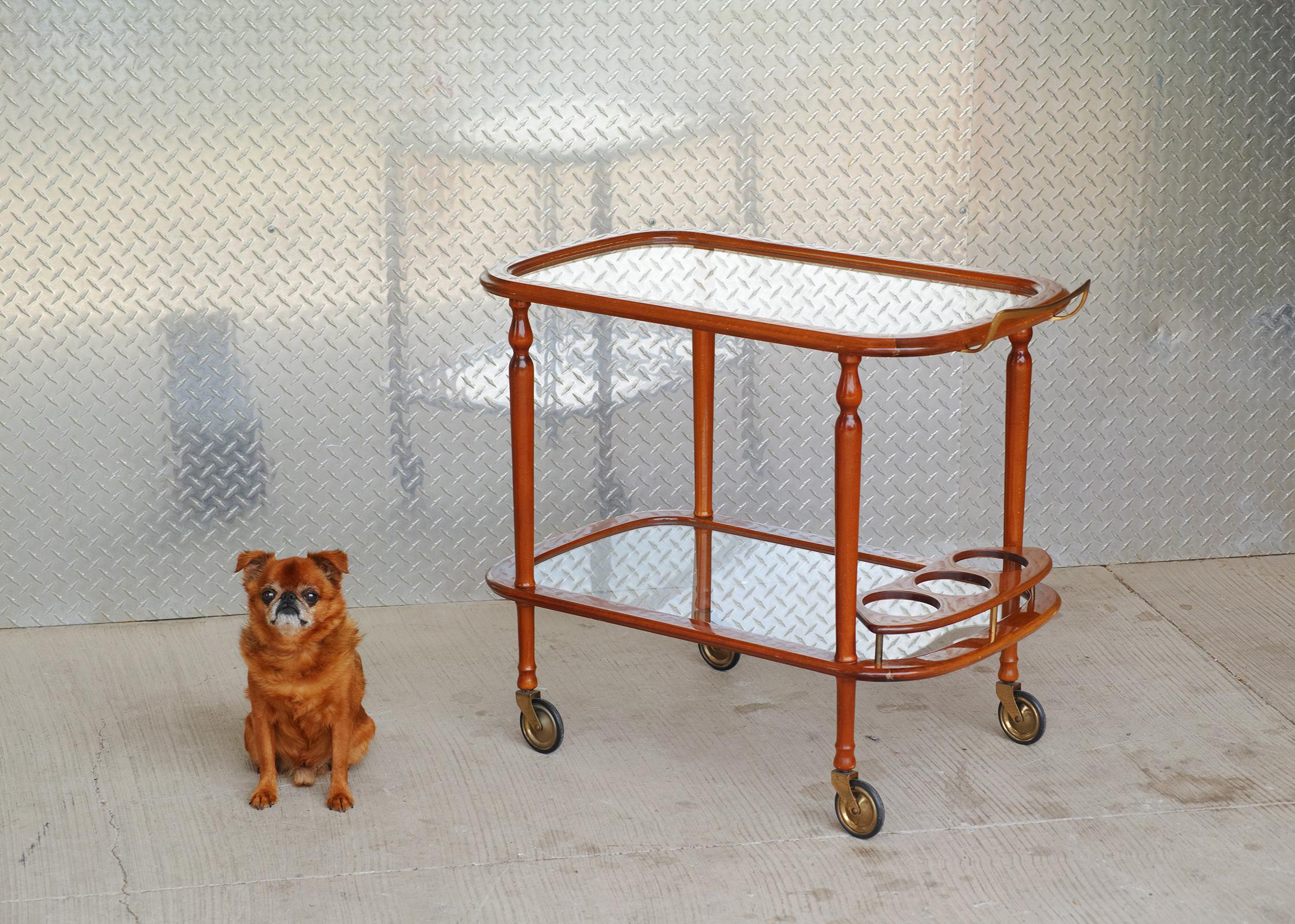 For your consideration is this all-original Italian lacquered bar cart dating from the 1960s. It features a sturdy yet lightweight solid wood frame with original finish and two tier inset glass tops. The lower tier features three bottle holders. The