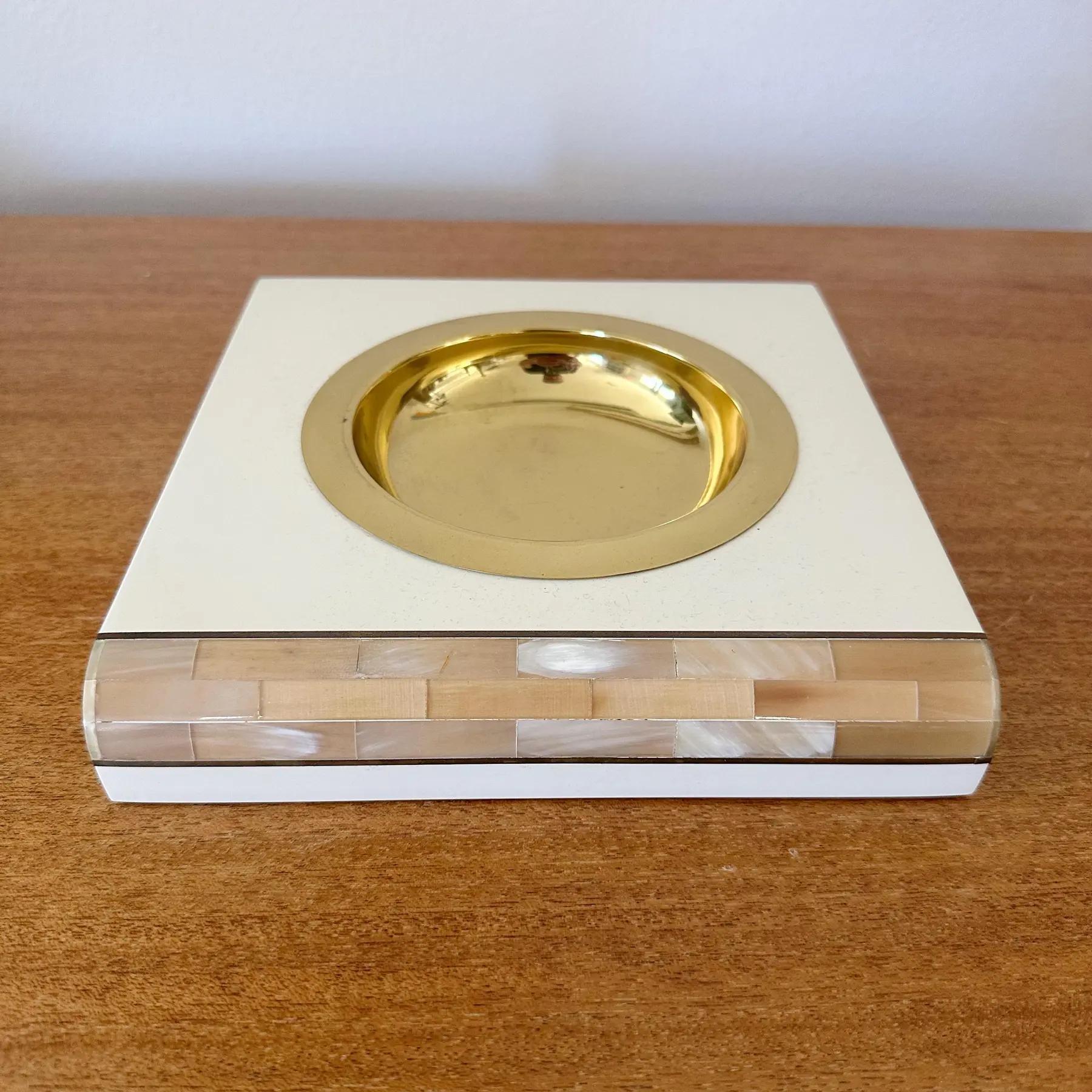 Colector lacado italiano, años 80. Cuerno teselado con incrustaciones de latón y bandeja de latón acabada en laca crema. Adecuado como cenicero, recogedor u objeto decorativo. Tres disponibles en distintos tamaños; consulta los listados para más