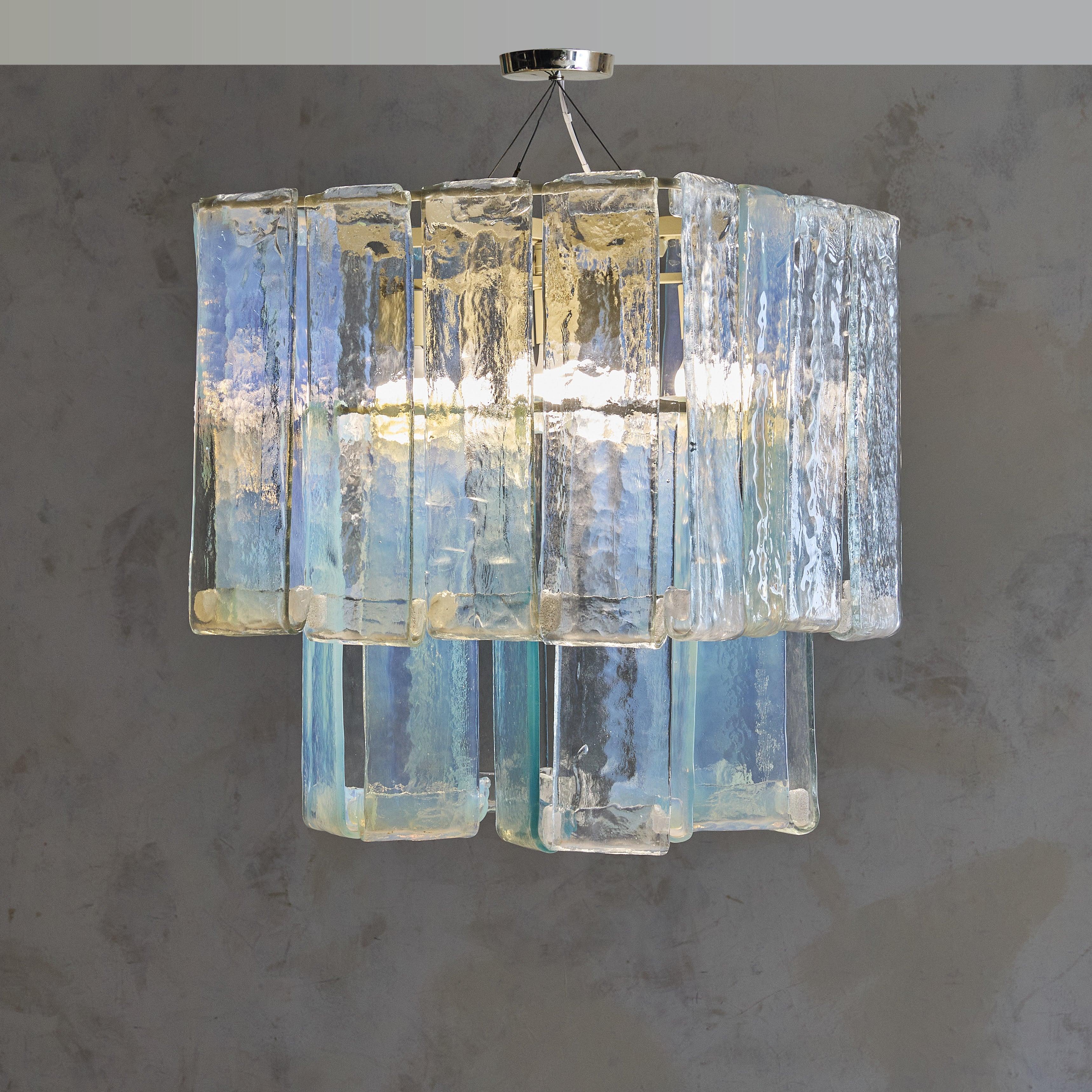 The ‘Laguna’ model chandelier, designed by Renato Toso for Fratelli Toso in the 1960s, exemplifies mid-century Italian glass artistry. Crafted with 28 pieces of iridescent Murano glass, this fixture glows with pearlescent hues, shifting between soft