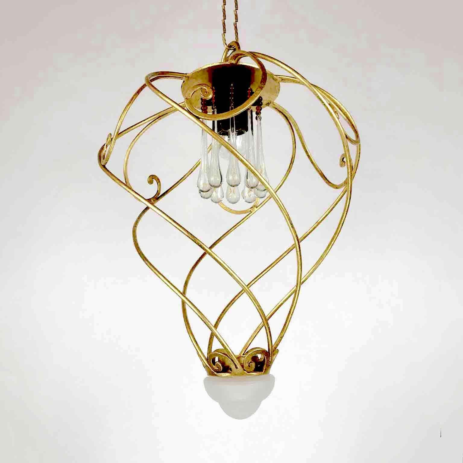Vintage Italian Florentine chandelier with a leaf-gilded iron structure, cage shaped realized with spiral scrolls decorated with a finial frosted glass elements, the E27 light in the upper part is surrounded by a ring of crystal pendant drops. This
