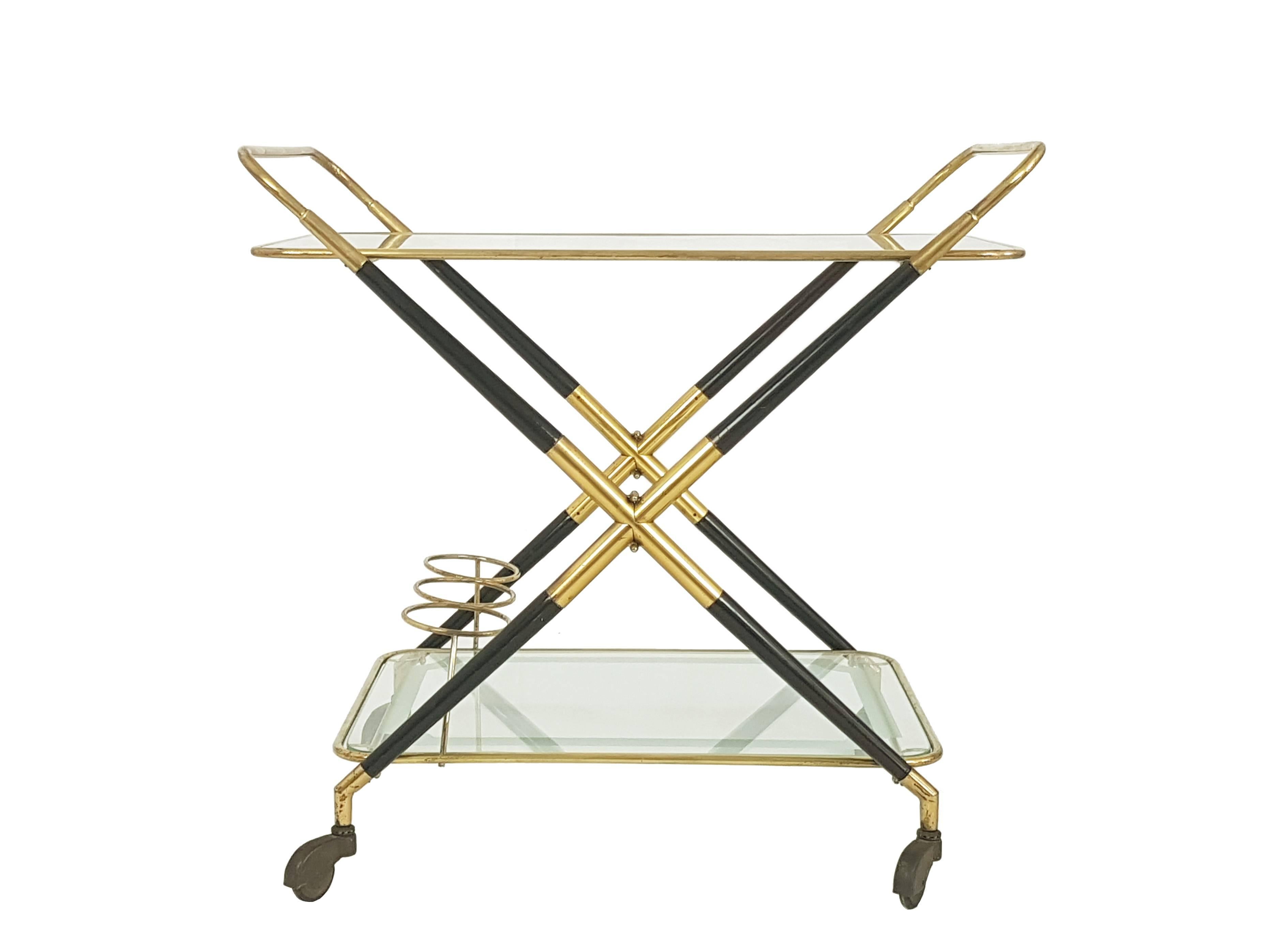 This serving trolley is made from a brass and laquered wood structure, supporting two removable glass shelves with brass edging. All sitting on brass and rubber wheels. Thanks to its useful brass joint the serving cart can be folded. Each glass