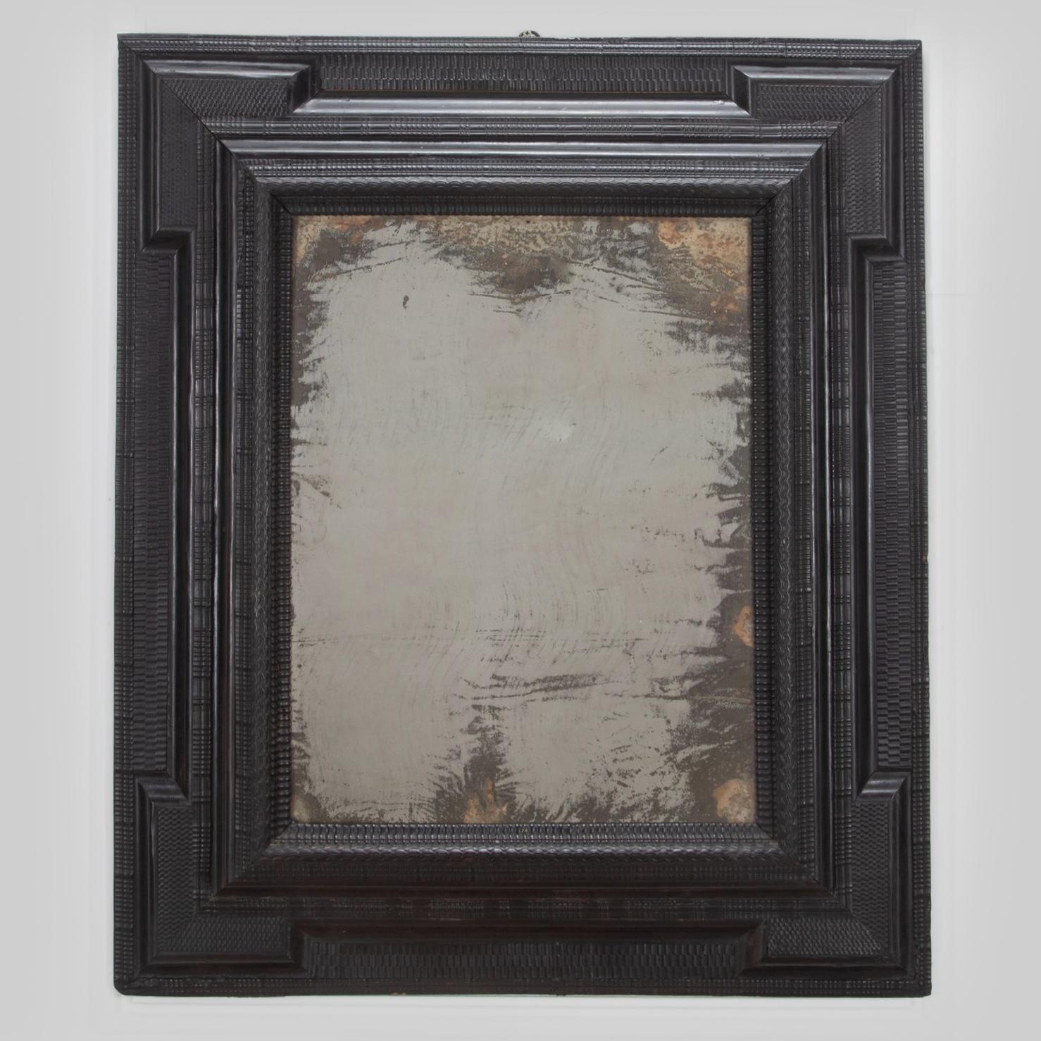 A large late 17th Century Italian ebonised fruitwood (probably pear) graduated cushion mirror. 

With an abundance of various carved mouldings including ripple, wave and basket weave, surrounding a wonderfully foxed mercury glass plate. A fabulous