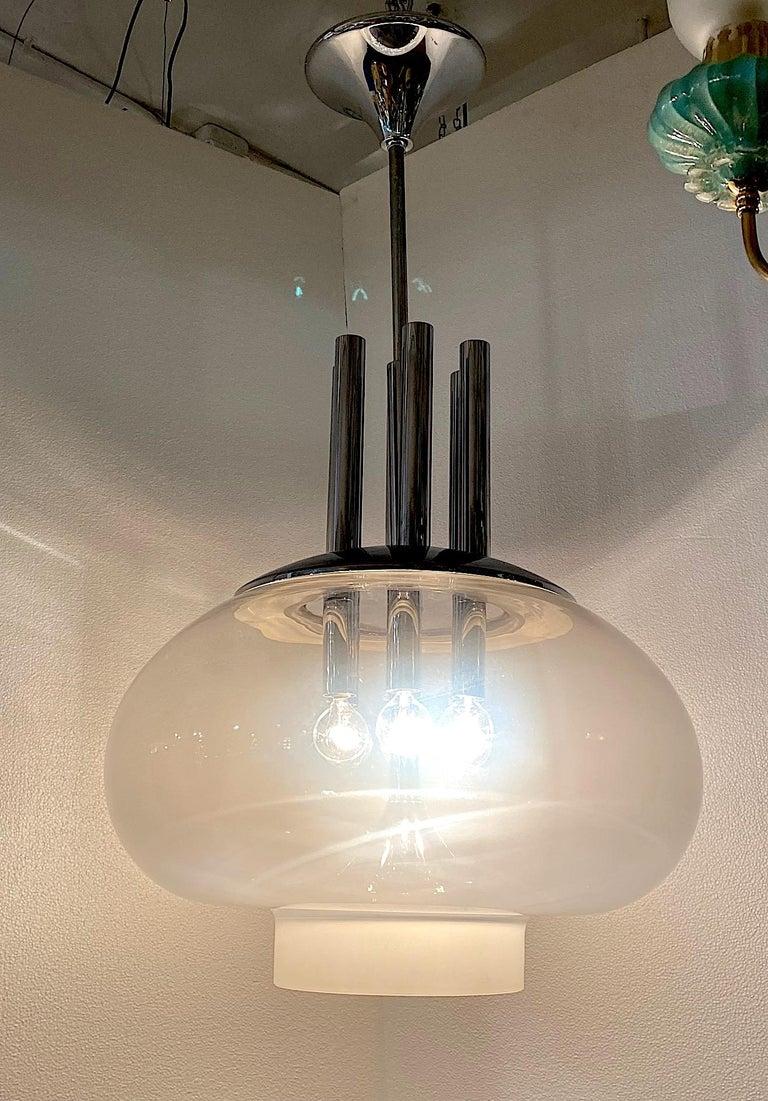 An incredible Italian sculptural pendant light from the 1970s. The chrome frame has six candelabra sockets housed inside a large 21.5 inch diameter opaque white mushroom top shade. The shade is hand blown with a layer of white glass over clear glass