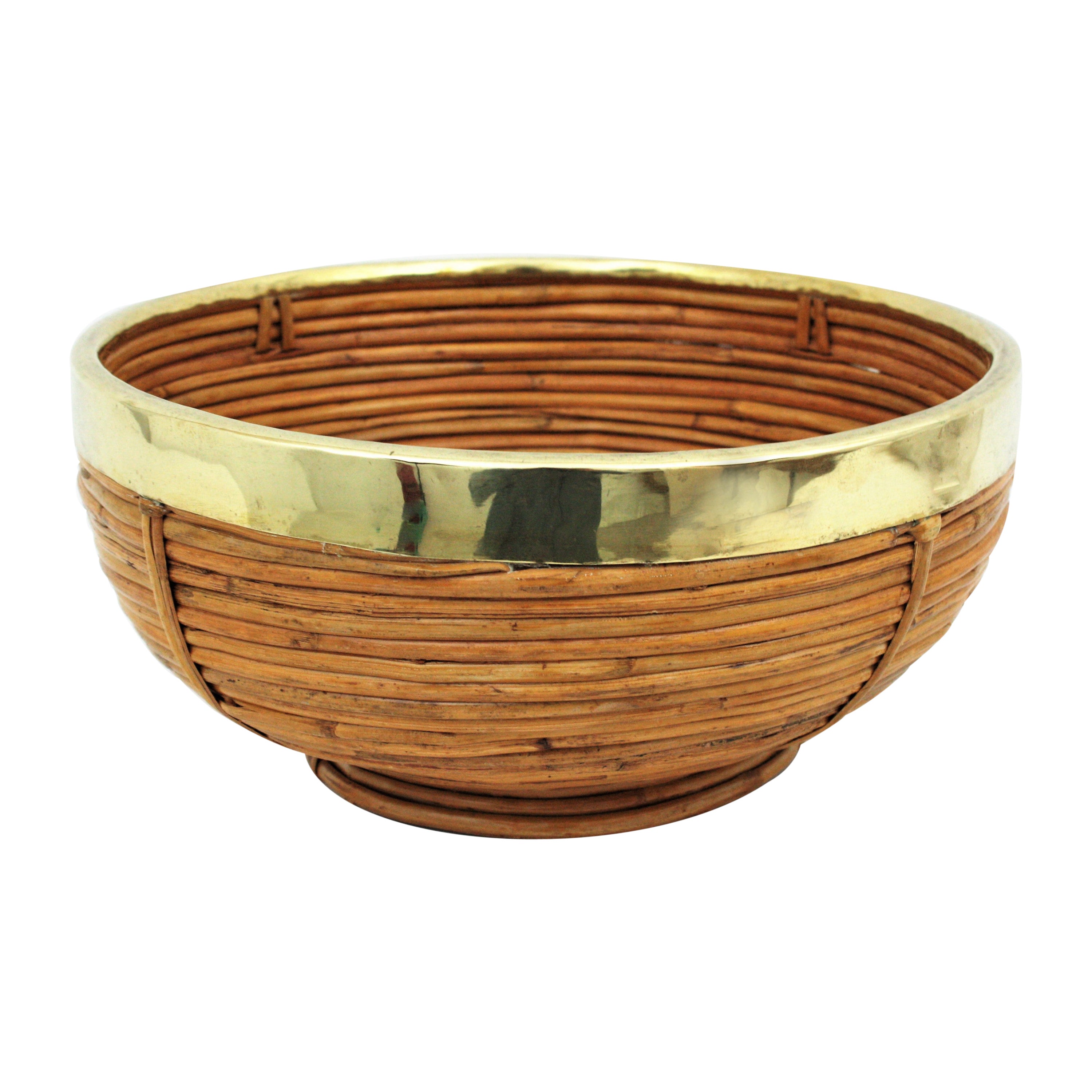 Ciotola, centrotavola o cesto di grandi dimensioni in rattan e ottone, in stile Mid-Century Modern.
La parte superiore è ricoperta da una cornice in ottone.
Realizzato a mano in Italia, anni '70. 
Utilizzala come fruttiera o centrotavola per