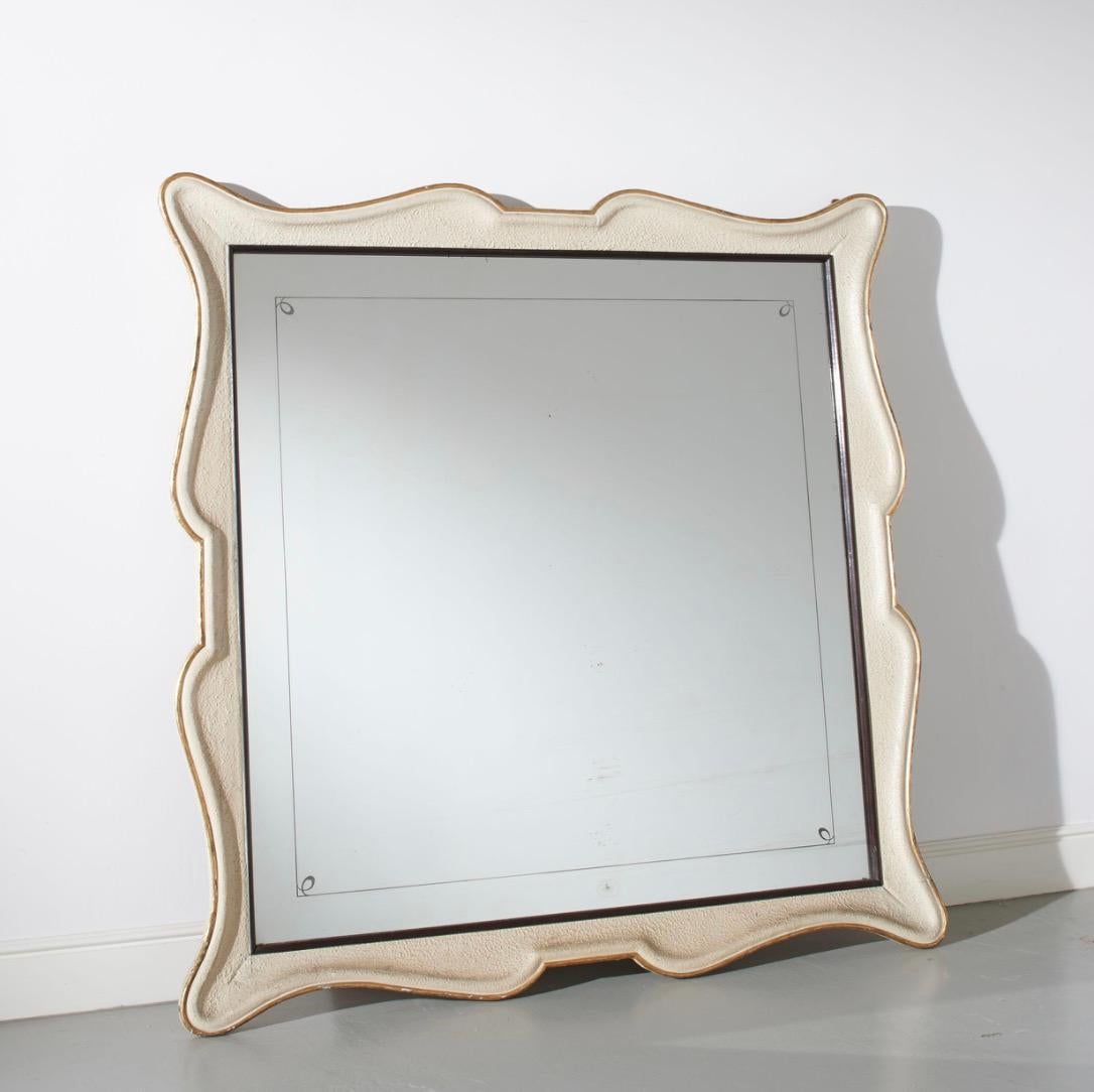 Specchio da parete italiano molto grande e di belle proporzioni, circa 1940.
La cornice è rifinita in crema testurizzato con bordi in foglia d'oro e conserva lo specchio in vetro originale, con un raffinato bordo decorativo quadrato. 
