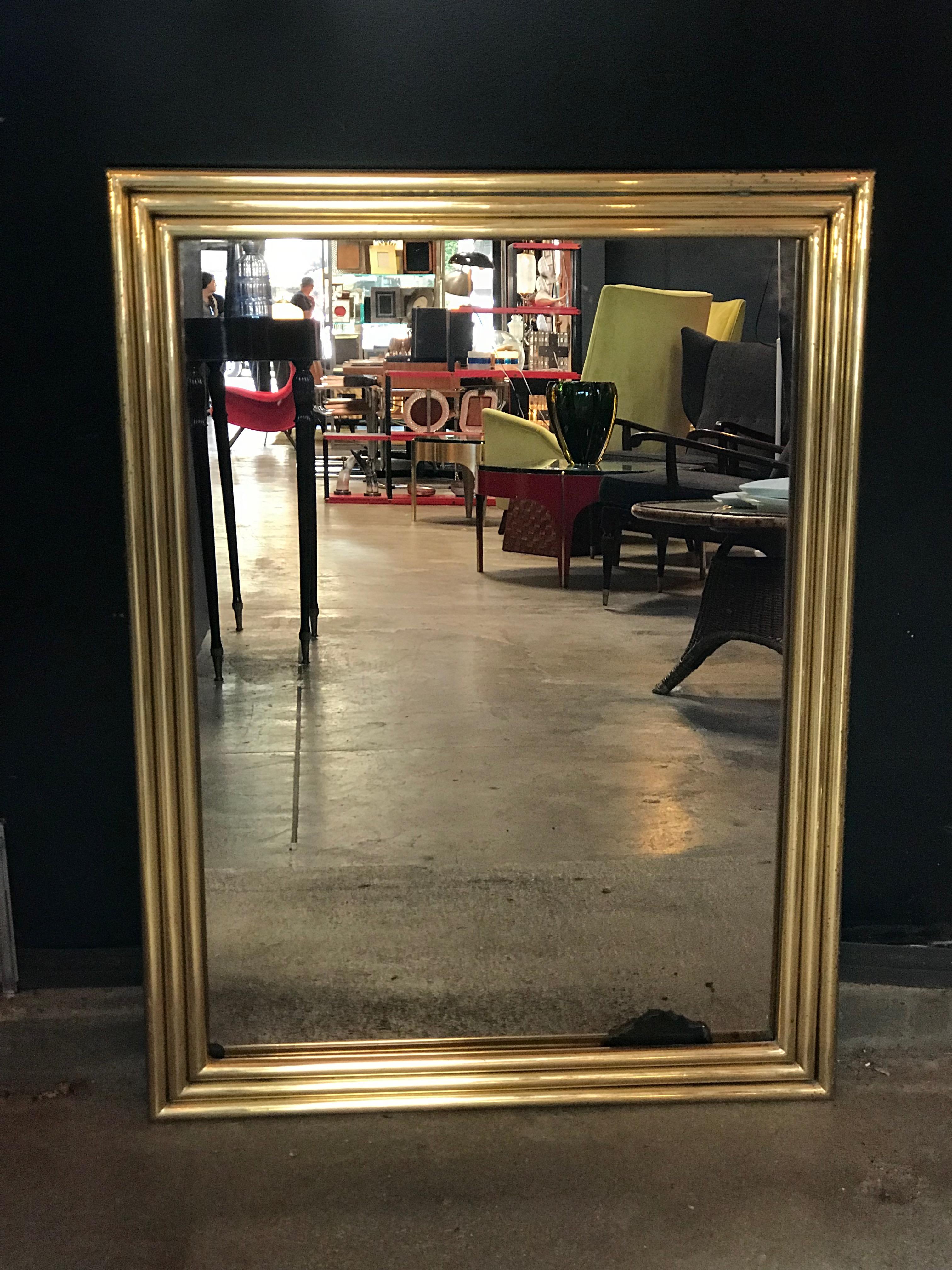 An Italian mirror with brass surround from the midcentury. This simple and elegant vintage Italian mirror features a rectangular shape with brass surround, which has a lovely patina throughout. This is a good sized mirror. The clean lines allowing