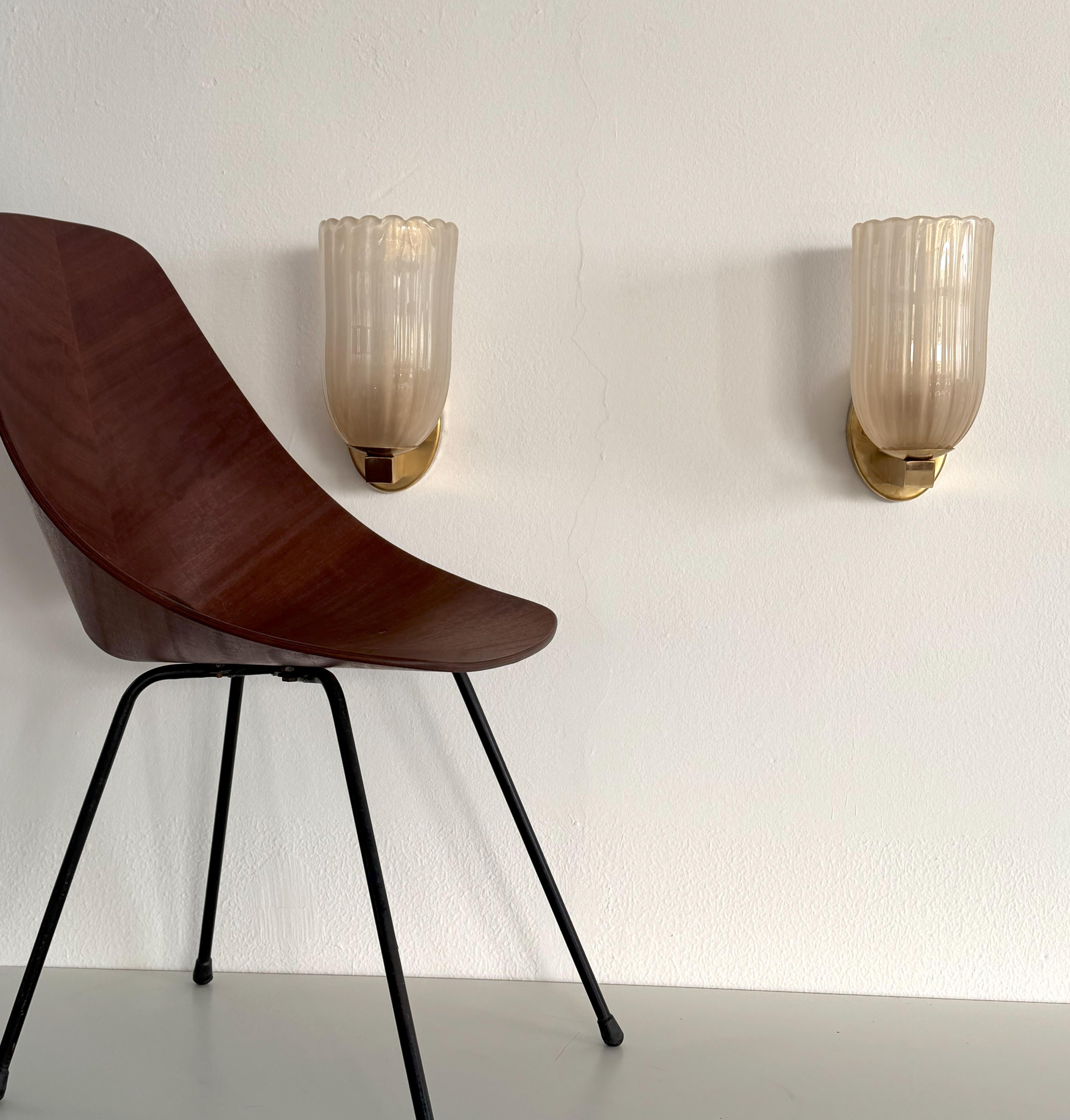 Apliques italianos grandes de cristal de Murano y latón en estilo Art Déco, años 90

Precioso conjunto de dos magníficas lámparas de pared grandes fabricadas con una sólida base de latón y ligeros cristales ondulados de Murano de color crema claro