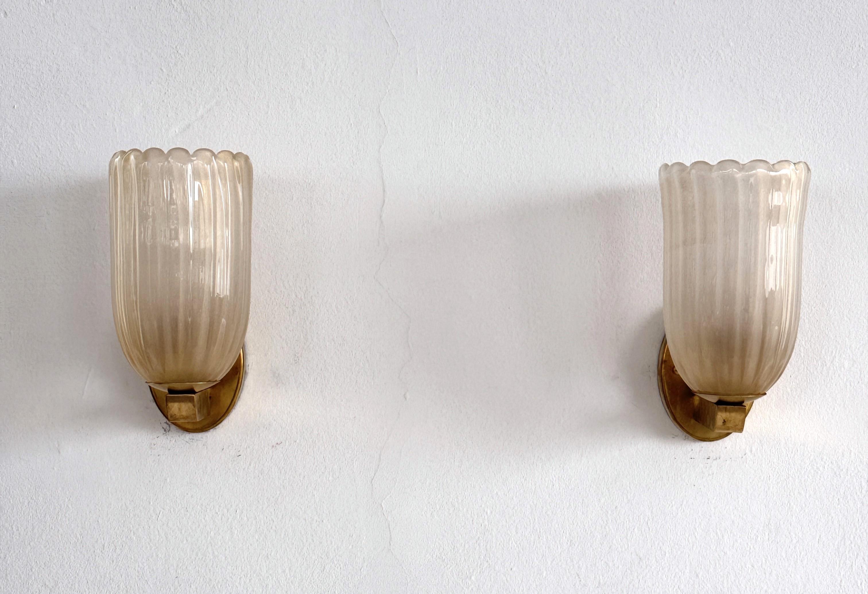Grandi lampade da parete italiane in vetro di Murano e ottone in stile Art Déco, anni '90

Bellissimo set di due splendide lampade da parete di grandi dimensioni realizzate con una robusta base in ottone e leggeri vetri ondulati di Murano di colore