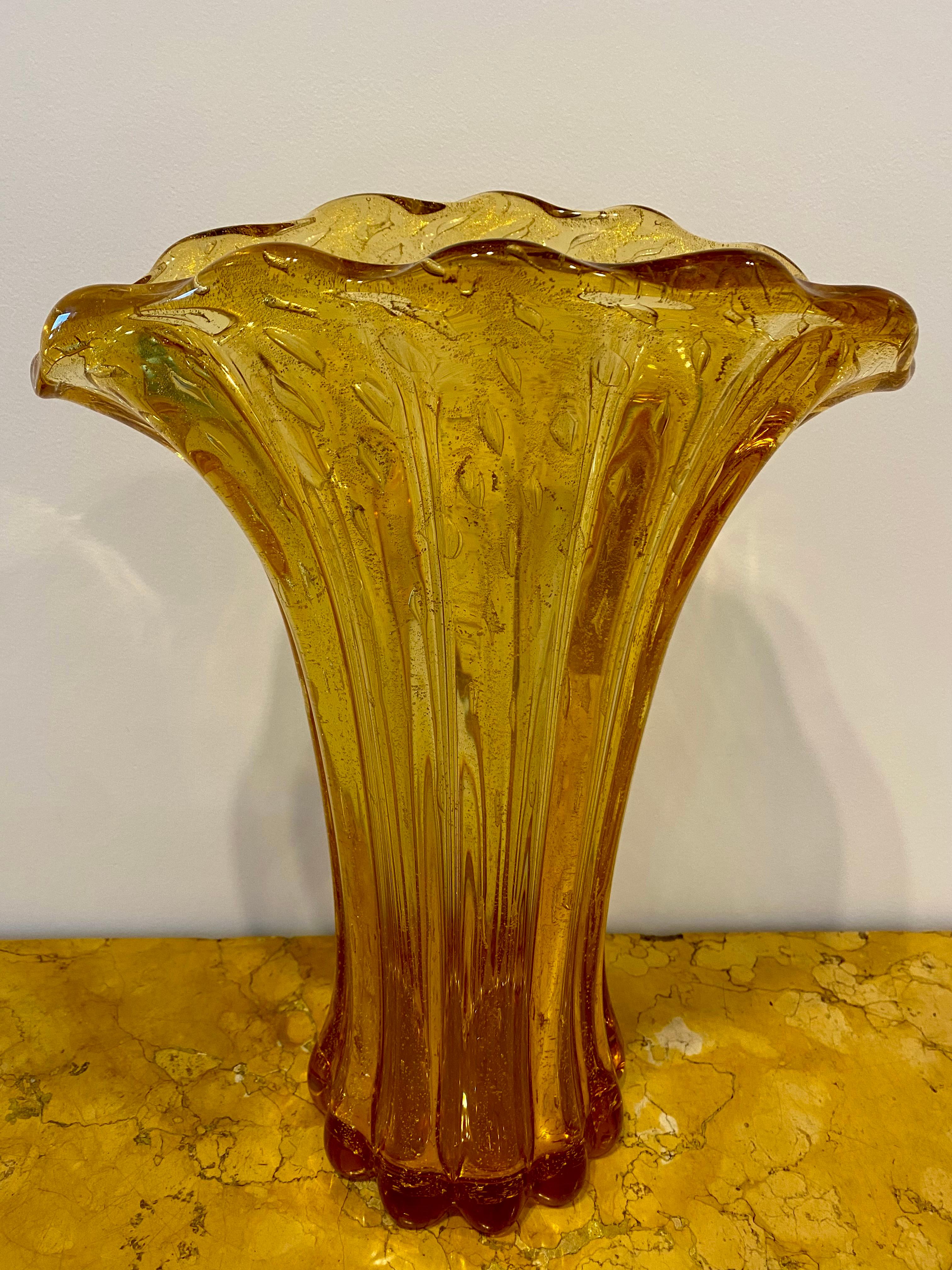 Italian Large Murano Sommerso vase, Signed Simone Mian, Circa 1980

This Italian Murano Sommerso vase with a wavy top fan shape, and long convex lines rounded up to a scalloped base is amber in color with golden spangles and controlled air