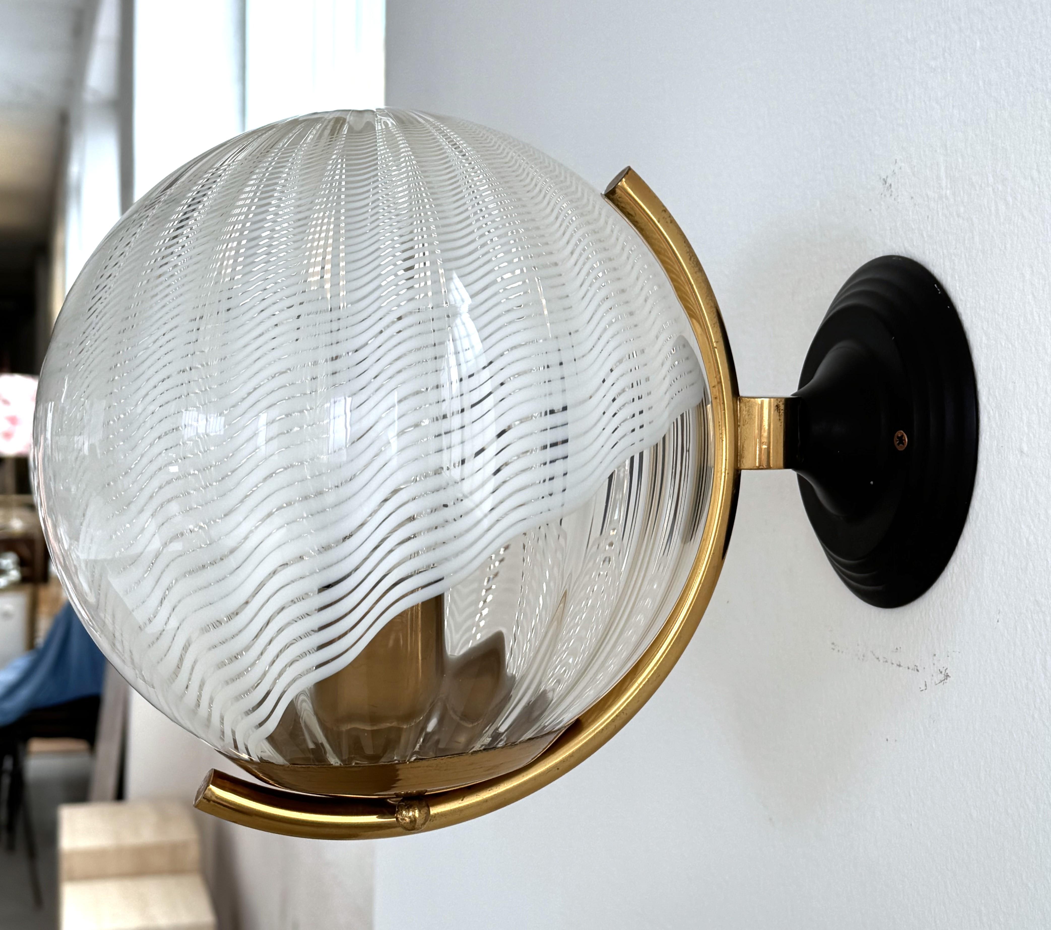 Italian Large Wall Lights with White Striped Wavy Glass Globes, 1970s

Beautiful large pair of wall lamps, made in Italy in the 1970s.
The spherical glass shades have a wave shape with irregular white stripes running across them.
Due to the wave