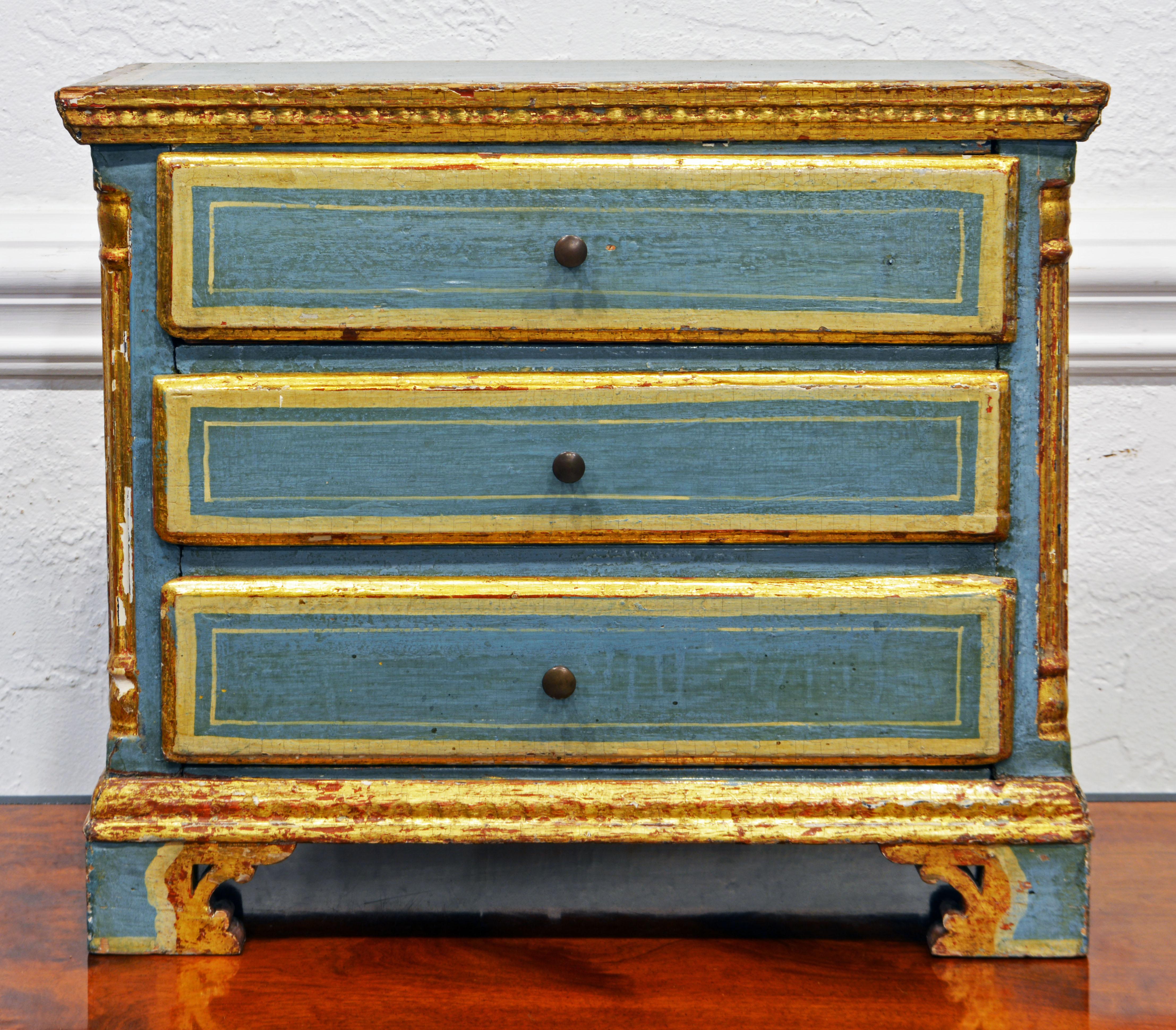 This attractive Italian late 18th century paint and gilt miniature chest of drawers features thre drawers flanked by giltwood corner colors resting on carved parcel gilt bracket feet. It is of wonderful proportions and color and could be used on a