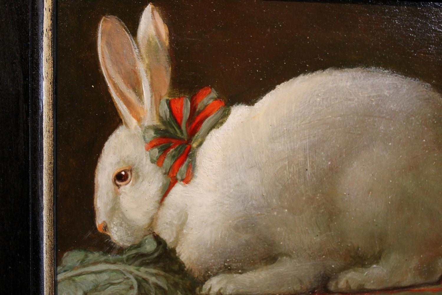 This lovely oil on board still life painting features a cute white rabbit eating a lettuce leaf. The bunny is crouched on a table with a red and green checkered tablecloth and has a nice fabric bow at the neck, the ribbon has the same colors as the